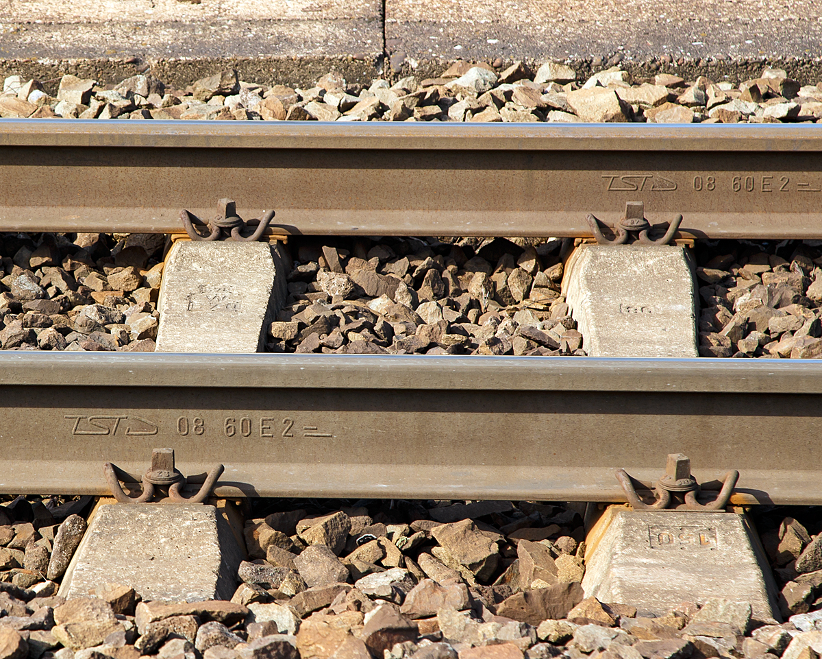 Schienen-Walzzeichen, fotografiert am 25.03.2017 in Koblenz-Moselwei� (Moselstrecke).
Anhand des Walzzeichen sieht man:
Den Hersteller: TSTD =Thyssen Schienen Technik GmbH (vormals ATH August Thyssen-H�tte), war bis 2013 das letzte verbliebene Schienenwalzwerk in Deutschland.
Das Herstellungsjahr: 08 = 2008
Das Schienenprofil: 60E2 (�hnlich UIC 60), Schiene 60,03 kg/m, H�he 172 mm, Fu�breite 150 mm, Schienenkopfbreit 72 mm   
Die Werkstoffg�te: ein kurzer �ber einem langen Strich = Verschlei�feste Qualit�t 900A (W.-Nr. 1.0623), neue Stahlg�te EN 13674-1 R260 Mindestzugfestigkeit 880N/mm�, BHN H�rtegrad min. 260 (entspr. ca. 27 HRC). 
Es handelt sich um einen Kohlenstoff-Mangan-Stahl (C-Mn), 0,62 bis 0,80 % Kohlenstoff, 0,70 bis 1,20 % Mangan, 0,15 bis 0,58 % Silizium und bis zu 0,15 % Chrom.