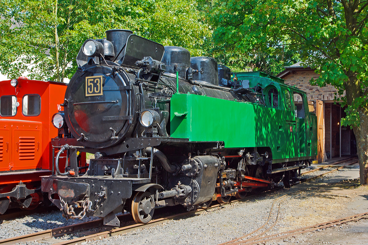Schmalspur-Dampflokomotive Nr. 53 der ehemaligen Rhein-Sieg-Eisenbahn-AG  (RSE) / Bröltalbahn am 08.06.2014 im Museum Asbach (Ww), dem ehemaligen Bröltalbahn-Lokschuppen.

Bei dieser Tenderdampflokomotive handelt es sich um die größte, schwerste und leistungsfähigste ehemalige Lok der Rhein-Sieg Eisenbahn (RSE), gleichzeitig ist sie eine der modernsten Schmalspurdampfloks Deutschlands.

Die Lok wurde 1944 unter Fabriknummer 10175 von der Firma Jung in Jungenthal bei Kirchen/Sieg gebaut. 

Technische Daten:
Hersteller:  Lokomotivfabrik Jung/Jungenthal bei Kirchen/Sieg
Fabriknummer:  10175
Baujahr: 1944
Spurweite: 785 mm
Bauart:  1'D1' h2t
Baujahr: 1944
Leergewicht: 40,5 Tonnen
Dienstgewicht: 51 Tonnen
Wasser: 4,6 m³
Kohle: 2,0 Tonnen
Länge über Puffer: 11.345 mm
Breite:  2.260 mm
Höhe ü. SO:  3.370 mm
Höchstgeschwindigkeit: 50 km/h
max. Kesselüberdruck:  15 bar
Rostfläche:  2,0 m²

Ausrüstung:
Heusinger-Steuerung, Schieber Bauart Karl-Schulz, Antrieb auf 4. Kuppelachse, 1 und 4 Kuppelachse gebremst, 2. + 3. Kuppelachse um ± 25 mm seitenbeweglich; Nachlaufachse mit Außenrahmen und Zug- / Stoßeinrichtungen, Laufachsen als Bisselachsen, vorn ± 150 mm, hinten ± 200 mm; genieteter Kessel mit Stahlfeuerbüchse, Wagner-Heißdampfregler, genieteter Blechrahmen, 21,8 % ausgeglichene Massen, Strube Dampfstrahlpumpe (125 l/min), S.H.G. Abdampfstrahlpumpe (52/86 l/min), Einkammer-Druckluftbremse Bauart Knorr mit Zusatzbremse und Handhebelbremse, zweistufige Luftpumpe, Druckluftsandstreuer, Dampfheizung-Anschluß, Lichtmaschine

Geschichte:
Für den steigenden Basaltverkehr aus den Brüchen des Westerwalds zu den Reichsbahn-Übergabebahnhöfen Hennef und Siegburg und zum Rheinhafen in Beuel benötigte die RSE Ende der dreißiger Jahre neue Lokomotiven. Die C-Kuppler von Jung und O&K aus Zeit der Jahrhundertwende waren zu klein und veraltet, die drei Jung-D-Kuppler wurden für Rollwagenzüge benötigt, und die vier 1'D1'-Tenderloks aus den zwanziger Jahren (Jung und Borsig) reichten allein nicht aus.

So bestellte die Direktion 1939 bei der Lokfabrik Jung/Jungenthal zwei Neubaudampfloks, die den großen Verkehrsbedürfnissen entsprechend völlig neu konstruiert wurden und die Nummern 53 und 54 tragen sollten. Während der Zeit des zweiten Weltkriegs konnte eine solche Bestellung nur mit kriegswichtigen Transportgütern begründet werden, die sich bei der RSE in Form von Basalt für den Bau von Befestigungen und in U-Boot-Batterien der Bleihütte Luise (Krautscheid) fanden. Um die für den Bau benötigten Metallkontingente genehmigt zu bekommen, mußten erst einmal 60 Tonnen Schrott für 40 Tonnen Lokgewicht gesammelt werden. Die Kriegsereignisse behinderten den Bau so sehr, daß man zunächst nur eine Lok in Angriff nahm. Bereits 1943 erfolgte die Druckprobe des Kessels, aber die Fertigstellung der gesamten Lok verzögerte sich bis 1944. Am 12. Juni 1944 kam sie in Hennef an, aber erst am 31. Januar 1945 konnte die erfolgreiche Probefahrt nach Waldbröl und Asbach durchgeführt werden, die Abnahme erfolgte zwei Tage später.

Die 53 kam sofort in den Betriebsdienst und geriet während einer Fahrt durch das Bröltal im März '45 unter Tieffliegerbeschluß. Nur der Geistesgegenwart des Personals war zu verdanken, daß keine großen Schäden oder sogar Totalzerstörung eintraten. Die Einschußstellen sind noch heute sichtbar!

Nach Ende der Kampfhandlungen und langsamer Wiederaufnahme des Bahnbetriebs mit den üblichen Einschränkungen wurde die Lok bei ihrem Hersteller Jung repariert und kam mehr schlecht als recht wieder ans laufen. Die kriegsbedingte Verwendung minderwertiger Materialien zeigte nun Folgen, vor allem die stählerne Feuerbüchse bereitete viele Probleme. Die Jahre 1951 bis 1954 verbrachte sie im Herstellerwerk, erst nach Austausch der Feuerbüchse gegen eine solche aus Kupfer zeigte die 53 allgemein befriedigende Leistungen. Aber sie hatte Macken und war nicht leicht zu handhaben, weshalb nur ausgesuchte Lokführer mit ihr fahren durften, die sehr stolz auf ihre prächtige Maschine waren. 

1957 erfolgte in der Hennefer Werkstatt ein Umbau zum Betrieb mit Ölfeuerung, welche sich zuvor bei Lok 32 sehr bewährt hatte. Im Gegensatz zur DB, die für ihre später umgebauten Ölloks das zähe Bunkeröl C verwendete, benutzte die RSE das leichtere B-Öl. So entfiel die Notwendigkeit einer ständigen Ölheizung, mit der zähe Öle fließfähig gemacht werden müssen. Nun konnte auch der Heizer eingespart werden, die Bedienung des Kessels hatte der Lokführer mit zu verantworten. Bei Streckenfahrten fuhr nun der Zugführer zwecks Streckenbeobachtung im Führerstand mit, wodurch auch die Mitnahme des Packwagens entfallen konnte.

Zur noch rationelleren Betriebsdurchführung beschaffte die RSE 1959/60 drei Dieselloks vom O&K-Typ MV8 mit je 130 PS Leistung. Die anfällige 53 kam immer seltener zum Einsatz, ihre letzte Fahrt ist für den 17.8.1966 verbürgt. Zuvor war sie längere Zeit arbeitslos, die letzten regulären Einsätze fanden an neun Tagen im November 1965 statt. Ein letztes Probeheizen führte das Personal am 16.8.66 durch, am nächsten Tag bewegte sich die Lok zum letzten Mal aus eigener Kraft.
Weitere Informationen: http://www.museum-asbach.de/index.html
