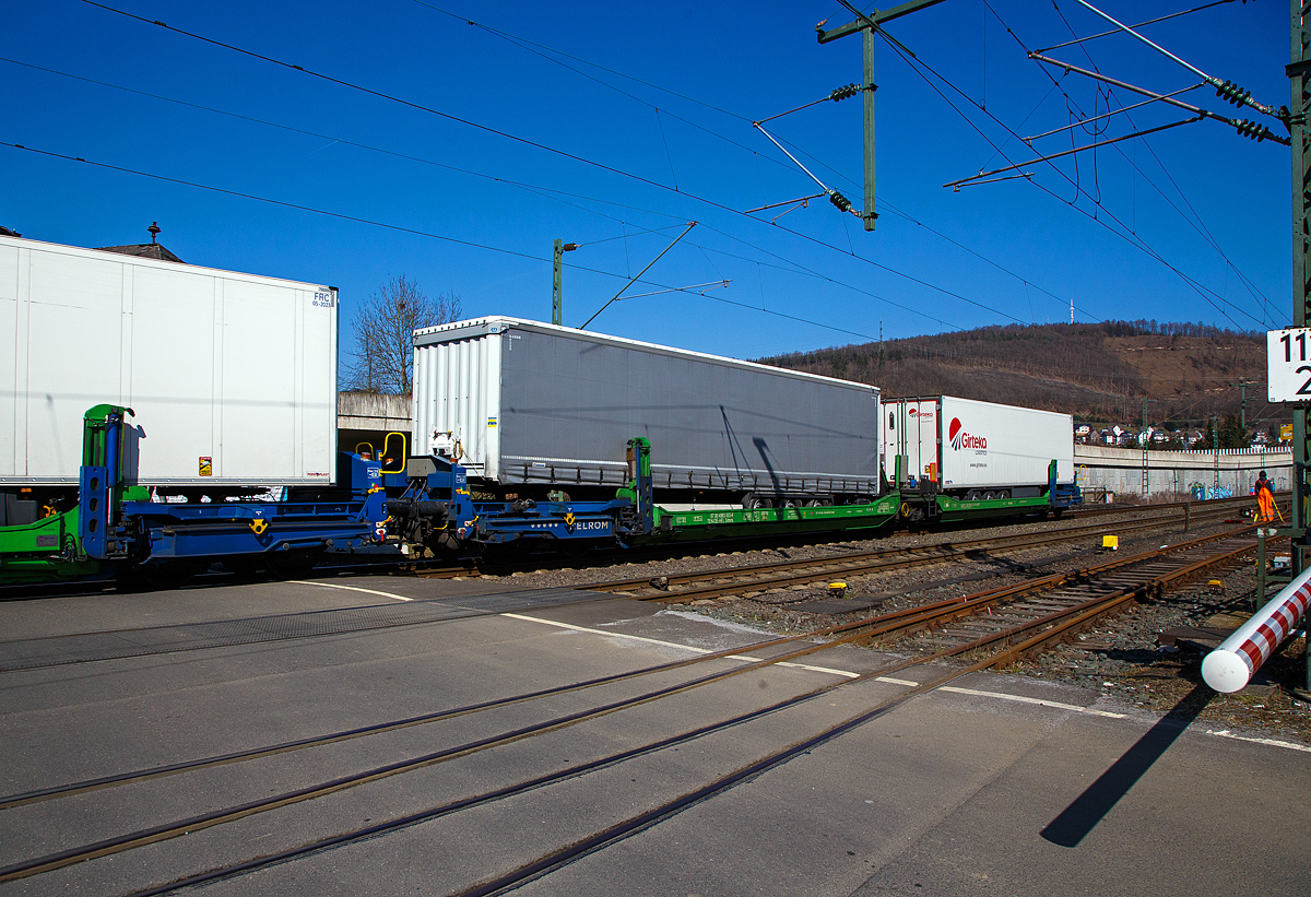 Spezieller sechsachsiger Gelenk-Taschenwagen System HELROM, 87 80 4993 003-4 D-HEL, der Gattung Sdmrs, der HELROM Trailer Rail am 24.03.2021 im Zugverband bei der Durchfahrt in Niederschelden. 

Der Clou bei HELROM sind neuartige Transportwaggons, die keine teuren Kran- oder Verladeeinrichtungen brauchen. Dieses Megaswing-System ist ein spezieller Taschenwagen mit schwenkbaren Aufnahmewannen f�r Sattelauflieger. Hydraulikst�tzen dienen als Stabilisierung, wenn die Wanne nach links oder rechts ausschwenkt. Die Beladung der Wanne mit einem Sattelauflieger erfolgt r�ckw�rts. Nach Absatteln des Sattelaufliegers wird die Wanne angehoben und schwenkt wieder ein. Der Sattelauflieger wird leicht abgesenkt und mit dem Waggon fest verbunden, er ist nun auf dem Waggon sicher verstaut. Die Technik ist im Waggon verbaut.

TECHNISCHE DATEN:
Hersteller: G�k Yapi  (T�rkei)
Spurweite: 1.435 mm
L�nge �ber Puffer:	34.230 mm
Drehzapfenabstand: 2 x 14.200 mm
Achsabstand im Drehgestellen: 1.800 mm
Laufraddurchmesser: 920 mm (neu)
Eigengewicht: 45.200 kg 
Max. Zuladung bei Lastgrenze: 76,0 t (ab Streckenklasse D)
Max. Geschwindigkeit: 100 km/h (beladen) / 120 km/h (leer)
Kleinster befahrbarer Gleisbogen: R 75 m
Bremse: 2 x MH-GP-A (K)
Bremssohle: Cosid 810
Feststellbremse: Ja (auf ein Drehgestell)
Intern. Verwendungsf�higkeit: TEN CW
