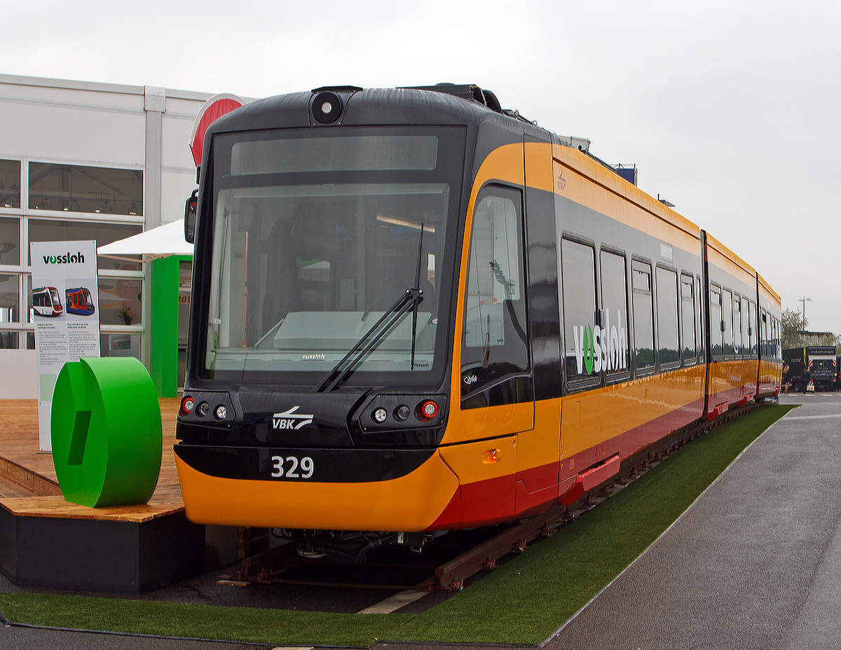 Vossloh „Citylink NET 2012“ (NET=Niederflur Elektrotriebwagen) f�r die Stadtbahnen Karlsruhe ein Einrichtungs-Gelenkfahrzeug, mit Hilfsfahrerstand am anderen Ende, wurde auf der InnoTrans 2014 (26.09.2014) pr�sentiert, hier der Triebwagen VBK 329.

Nach einer europaweiten Ausschreibung haben die Verkehrsbetriebe Karlsruhe (VBK) die Stadtbahnen im Oktober 2011 beim D�sseldorfer Traktionsspezialisten Vossloh Kiepe GmbH und seinem spanischen Schwesterunternehmen, dem Schienenfahrzeug-Hersteller Vossloh Rail Vehicles, bestellt. Das Auftragsvolumen umfasst rund 75 Millionen Euro. Es wurden 25 dieser Niederflur-Stadtbahnen bestellt, mit Option auf 50 weitere Fahrzeuge.  

Die Stadtbahnen vom Typ Citylink NET 2012 sind speziell auf die infrastrukturellen Gegebenheiten und die Charakteristik der Stadt und Region Karlsruhe zugeschnitten. Sie werden mit ihrer Ausstattung den wachsenden Anforderungen an Mobilit�t und Fahrkomfort gerecht. Der Fahrgastraum ist bequem �ber f�nf breite Doppelt�ren erreichbar (nur auf einer Fahrzeugseite, da es ein Einrichtungsfahrzeug ist). 

Mit der modernen Ausr�stung von Vossloh Kiepe verf�gen die Fahrzeuge �ber zuverl�ssige und innovative elektrische Technologie. Diese beinhaltet die komplette Antriebstechnik und Fahrzeugsteuerung, die Bordnetzversorgung, Heizung / Klima / L�ftung f�r den Fahrgastraum und den Fahrerraum sowie die Zugsicherungs- und Fahrgastinformationssysteme und Video�berwachung.

Der NET 2012 hat eine Einstiegsh�he von 345 mm und ist so die erste Train-Tram mit ultraflachem Fahrzeugboden. Damit kann das Fahrzeug an den entsprechend barrierefrei ausgebauten Bahnsteigen auch von mobilit�tseingeschr�nkten Fahrg�sten und Kunden mit Kinderwagen bodengleich betreten werden. Multifunktionsbereiche im Innenraum bieten Platz f�r Rollstuhlfahrer, Kinderwagen und Fahrr�der. Durch den hohen Niederfluranteil (wenig Stufen), tief positionierte Fahrscheinautomaten und Haltewunschsignalgeber, die farblich kontrastreich gestaltet sind, soll in der Bahn zus�tzliche Barrierefreiheit entstehen.

Besonders laufruhig und komfortabel sind die neuen Fahrzeuge au�erdem dank ihrer Luftfederung. Eine Klimaanlage sorgt im Sommer wie im Winter f�r angenehme Temperierung. Der Hersteller Vossloh Rail Vehicles hat seinen Citylink, den er in �hnlicher Ausf�hrung auch f�r Sheffield in England und Chemnitz im Osten der Republik baut, den Vorgaben der neuesten Crash-Norm entsprechend gefertigt. Unter der Frontverkleidung sind Puffer eingebaut, die bei einem Zusammensto� die entstehende Energie aufnehmen und das Fahrzeug besonders sicher machen. Trotz dieser Puffer kann der Fahrer durch eine tief gezogene Frontscheibe, speziell angeordnete Bedienelemente und den weit vorn geplanten Sitz eine 1,20 Meter gro�e Person bei einem Abstand von gerade einmal 30 Zentimetern noch sehen. Dies macht die neue Stadtbahn gerade im Innenstadtbereich zu einem  h�chst sicheren Fahrzeug .

Technische Daten:
Spurweite 1.435 mm
Achsformel: Bo’(2’)(2’)Bo’
Fahrzeugl�nge:  37.200 mm
Fahrzeugbreite:  2.650 mm
Fahrzeugh�he:  3.655 mm
Achsstand im Drehgestell: 1.900 mm
Kleinster bef. Halbmesser: 22 m
Anteil Niederflur: ca. 80 %
Einstiegsh�he 345 mm (bei 3/3-Beladung)
Leergewicht: ca. 57,5 t
Dienstgewicht: 83 t
T�ren:  5 Fahrgastraumt�ren
Sitzpl�tze: 107
Stehpl�tze:  137
Raddurchmesser :  680 mm (neu) / 600 mm (abgenutzt)
Fahrdrahtspannung: DC 750 V
Antriebe und Leistung:  4 x 125 kW
H�chstgeschwindigkeit: 80 km/h
Beschleunigung: 1,3 m/s� (durchschnittlich 0,6m/s�)
Bremsverz�gerung: 1,6 m/s� (Schnellbremsung: 2,73 m/s�)
Max. Gef�lle: 60 ‰
Kupplungstyp: Scharfenberg
Zulassung:  BOStrab / EBO
Besonderheiten: Fahrzeug erf�llt neue Crash-Norm / Luftfederung

