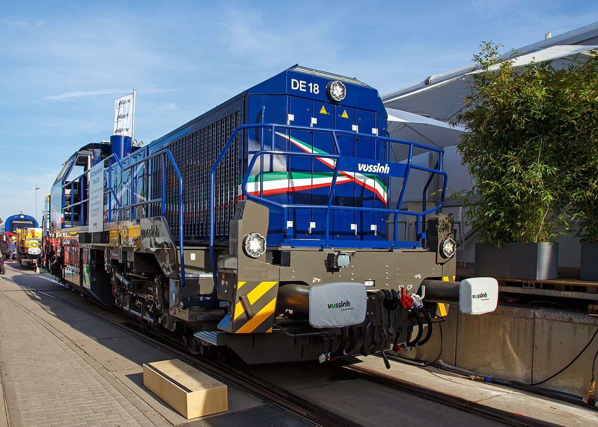 Vossloh Locomotives präsentierte auf der InnoTrans 2018 in Berlin (18.09.2018) seine vierachsige Dieselelektrische Lokomotive DE 18 Smart Hybrid. Hier in Form der für die Eiffage Rail (Frankreich) bestimmte  MF419  (92 87 4185 027-7 F-ERSF), die in Frankreich auch unter der Baureihe BB 79000 geführt wird. Die Lokomotiven wurden für den schweren Rangierdienst und Streckendienst mit hoher Einsatzflexibilität konzipiert.

Diese Lok wurde 2018 von Vossloh in Kiel unter der Fabriknummer 5502354 gebaut, auf der InnoTrans 2018 in Berlin präsentiert und dann an die Eiffage Rail S.n.c. als MF 419 ausgeliefert.

Die DE 18 ist eine relativ leichte Diesellokomotive (80 Tonnen), die überall auf dem französischen Bahnnetz eingesetzt werden kann. Sie ist für Güterzüge bestimmt, kann aber auch für Bahnnetz-Instandhaltungszüge eingesetzt werden (einschließlich auf Hochgeschwindigkeitsstrecken) und sie verfügt über eine besondere Funktionalität für Arbeiten im Tunnel.

Aufgrund des voranschreitenden technischen Fortschritts und den damit verbundenen neuen Möglichkeiten im Bereich der Energiespeicher und Antriebssysteme stehen Eisenbahnverkehrsunternehmen heute stärker denn je vor der Herausforderung, ihre bisherigen Fahrzeuge auf betriebswirtschaftliche Kostenoptimierung hin zu prüfen, und diese gegebenenfalls durch neue umweltfreundlichere, günstigere und leistungsoptimierte Systeme zu ersetzen. Bei der Entscheidung, eine neue Lokomotive für den Rangier- und/oder Streckendienst im Güterverkehr anzuschaffen, stehen neben den vorgesehenen Einsatzarten vor allem auch wirtschaftliche Aspekte und neue, verschärfte Umweltrichtlinien und Gesetze, die den Einsatz in bestimmten Bereichen und Arbeitsumfeldern für Lokomotiven mit hohem Schadstoffausstoß einschränken oder verbieten, im Vordergrund.

Diesen Zeitgeist trifft Vossloh Locomotives mit dem Angebot seiner zur SmartHybrid-Lok der weiterentwickelten DE 18. Bei ihr wird der 1.800 kW starke Dieselmotor um ein bis zu 150 kWh Batteriepaket ergänzt, wodurch Betreiber für Fahrten durch „Zero-Emission“-Bereiche im Tunnel oder während des Hallenbetriebs, je nach Lastprofil, über einen mehr als einstündigen Rangierbetrieb ohne Emissionen verfügen. Der erweiterte Start-Stopp-Support des Dieselmotors führt zu zusätzlichen Schadstoffreduzierungen und bringt effektive Einsparungen bei den Treibstoff und Wartungskosten.

Das Akkusystem mit neuester Lithium-Ionen-Technologie ist ohne komplexe Zusammenschaltung mit dem Dieselmotor im Bauraum des Zusatztanks integriert. Als Plug-In-Lösung wird die Batterie ökologisch sinnvoll über Nacht aus Fremdstromversorgung oder in Bereichen mit optimalem Dieselmotorwirkungsgrad über den Dieselmotor geladen. Je nach Einsatz des Akkus umfasst die Lebenszeit zwischen 3.000 und 6.000 Ladezyklen.

Eingefügt in den hochmodernen Antriebsstrang mit ETCS und Länderzulassungen für Deutschland, Frankreich und Luxemburg soll diese optionale Baugruppe 2019 getestet und 2020 für den kommerziellen Betrieb geliefert werden können. Die französische Akiem hat 44 dieser Dieselelektrischen Lokomotiven bei Vossloh Locomotives gekauft, die letzte soll bis Anfang 2022 geliefert werden. Die Akiem verleast diese an SNCF Réseau. Nach diversen Anpassungsarbeiten werden die Wartungslokomotiven BB 79000 von der SNCF Réseau schrittweise in Betrieb genommen. Die Vossloh-DE 18 werden Arbeiten auf Hochgeschwindigkeitsstrecken (LGV) durchführen und auch der TGV-Notfallversorgung dienen. 

TECHNISCHE DATEN:
Spurweite:  1.435 mm (Normalspur)
Achsformel:  Bo'Bo'
Länge über Puffer : 17.000 mm
Drehzapfenabstand: 7.940 mm
Achsabstand im Drehgestell: 2.400 mm
Raddurchmesser: 1.000 mm (neu) / 920 mm (abgenutzt)
Größte Höhe: 4.310 mm
Größte Breite: 3.080 mm
Höchstgeschwindigkeit: 120 km/h
Dieselmotor: 12 Zylinder-90°-V-Dieselmotor mit Registeraufladung, Ladeluftkühlung und Common-Rail-Einspritzung vom Typ MTU 12V 4000 R 84
Motorhubraum: 57.2 l (Ø 170 mm Bohrung x 210 mm Hub)
Motorabmessungen: 2.670 x 1.696 x 2.001 mm
Motorgewicht: 7.700 kg (trocken)
Abgasvorschriften: EU IIIB
Dieselmotorleistung: 1.800 kW
Dieselmotornenndrehzahl: 1.800 U/min
Traktionsleistung am Rad: 1.440 kW
Anfahrzugkraft: 300 kN
Dauerzugkraft: 230 kN bei 24,2 km/h
Dienstgewicht: 80 t
Kraftstoffvorrat: 4.000 l
Batteriepaket: 150 kWh
Fahrmotoren: 4 Asynchronmotoren
Stromrichter : IGBT
Elektrodynamische Bremsleistung: max. 1.450 kW
Bremse: Druckluftbremse KE-GP-E
Kleinster befahrbarer Bogenradius: 55 m
Zugsicherung: KVB, RPS, DAAT, TVM 430, GSM-R radio,
