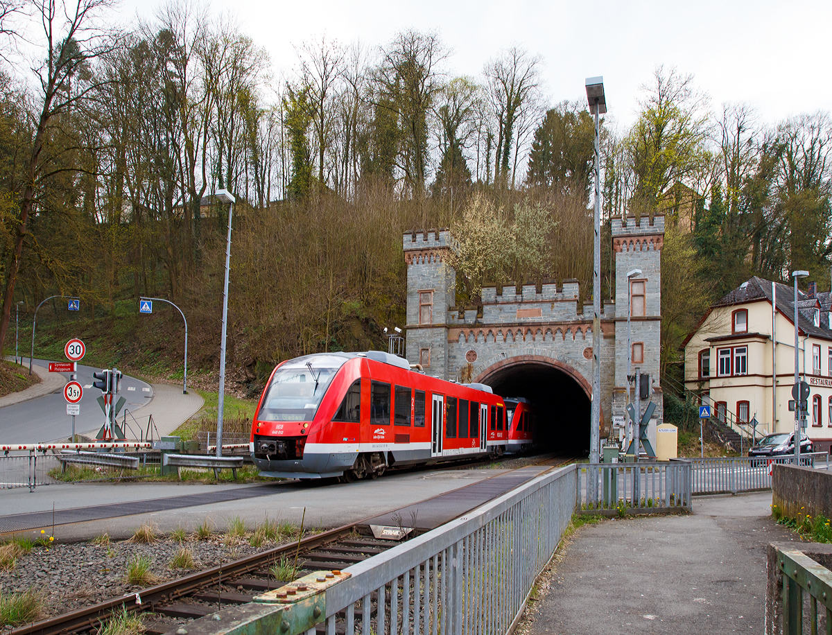 
Zwei gekuppelte Alstom Coradia LINT 27 (BR 640) der DB Regio  Lahn-Eifel-Bahn  verlassen am 10.04.2016 den 302 m langen Weilburger Tunnel durch das Nordportal und erreichen gleich, nach dem Überqueren der Lahn, den Bahnhof Weilburg. Die beiden Triebzüge verkehren als RE 25  Lahntalbahn   Koblenz - Limburg/Lahn - Wetzlar - Gießen (Umlauf RE 4287). 

Die Lahn umfließt Weilburg in einer weiten Schleife, deren Uferhänge zudem sehr steil und teilweise dicht bebaut sind. Eine Gleisführung entlang des Flusses verbot sich daher, so dass die Lahntalbahn die Weilburger Lahnschleife in einem 302 m langen Tunnel durch den Stadtfelsen abschneidet. Der Tunnel verläuft übrigens nahezu parallel zum Schiffstunnel, der schon im Jahr 1849 bei der Schiffbarmachung der Lahn nur wenige Meter entfernt durch den Felsen getrieben worden war, und dem nach 2002 neu gebauten Straßentunnel.

Nur an wenigen Stellen weist die Lahntalbahn räumlich derart beengte Verhältnisse auf wie hier: Nach der Tunnelausfahrt wird Landstraße Weilburg – Ahausen gekreuzt und gleich drauf die Lahn auf einer Eisengitterbrücke überquert und es beginnt der Bahnhofsbereich von Weilburg.