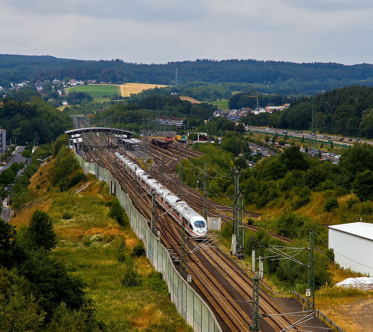 Zwei gekuppelte ICE 3 (BR 403) rauschen durch den ICE Bahnhof Montabaur in Richtung Köln. 

Hinten rechts im Rangier- und Abstellbereich stehen zwei Voith Gravita 10 BB (BR 26) der DB Cargo, sowie rechts davon die grüne LDS 293 511-2 mit dem Drehhobel D-HOB 4.0 (D-HOB 2500 IV) der Schweerbau.
