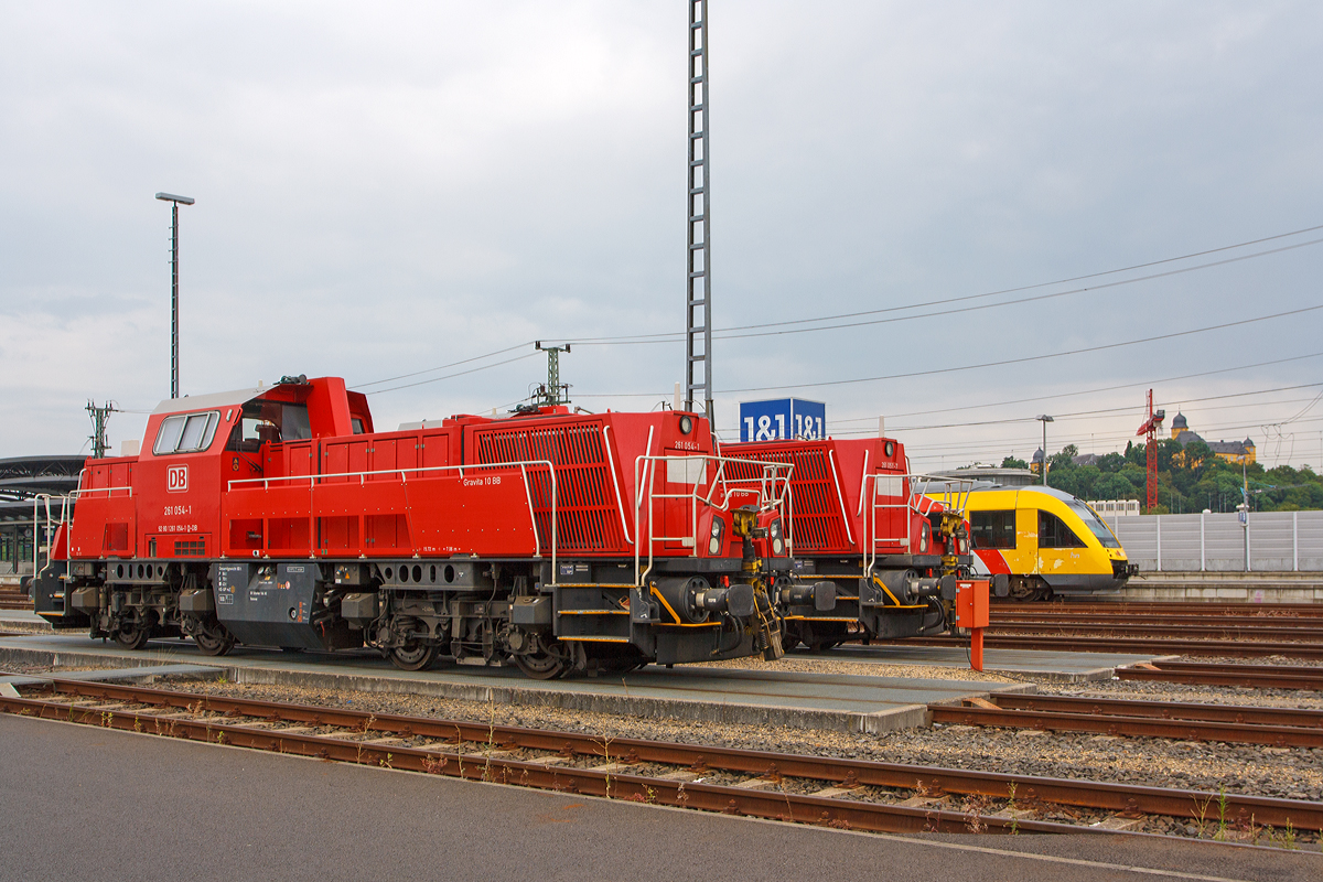 
Zwei Voith Gravita 10 BB, 261 054-1 und dahinter die 261 051-7der DB Schenker Rail abgestellt am 02.08.2014 beim Bahnhof Montabaur. Beide Voith Gravita 10 BB wurden 2011 gebaut, die 261 051-7 unter der Fabriknummer L04-10102 und die 261 054-1 unter der Fabriknummer L04-10105. 

Dahinter f�hrt der Vectus VT 206 ABp (95 80 0640 106-0 D-VCT) ein Alstom Coradia LINT 27 nach Siershahn (Westerwald)los, mittlerweile geh�rt der VT der HLB, 