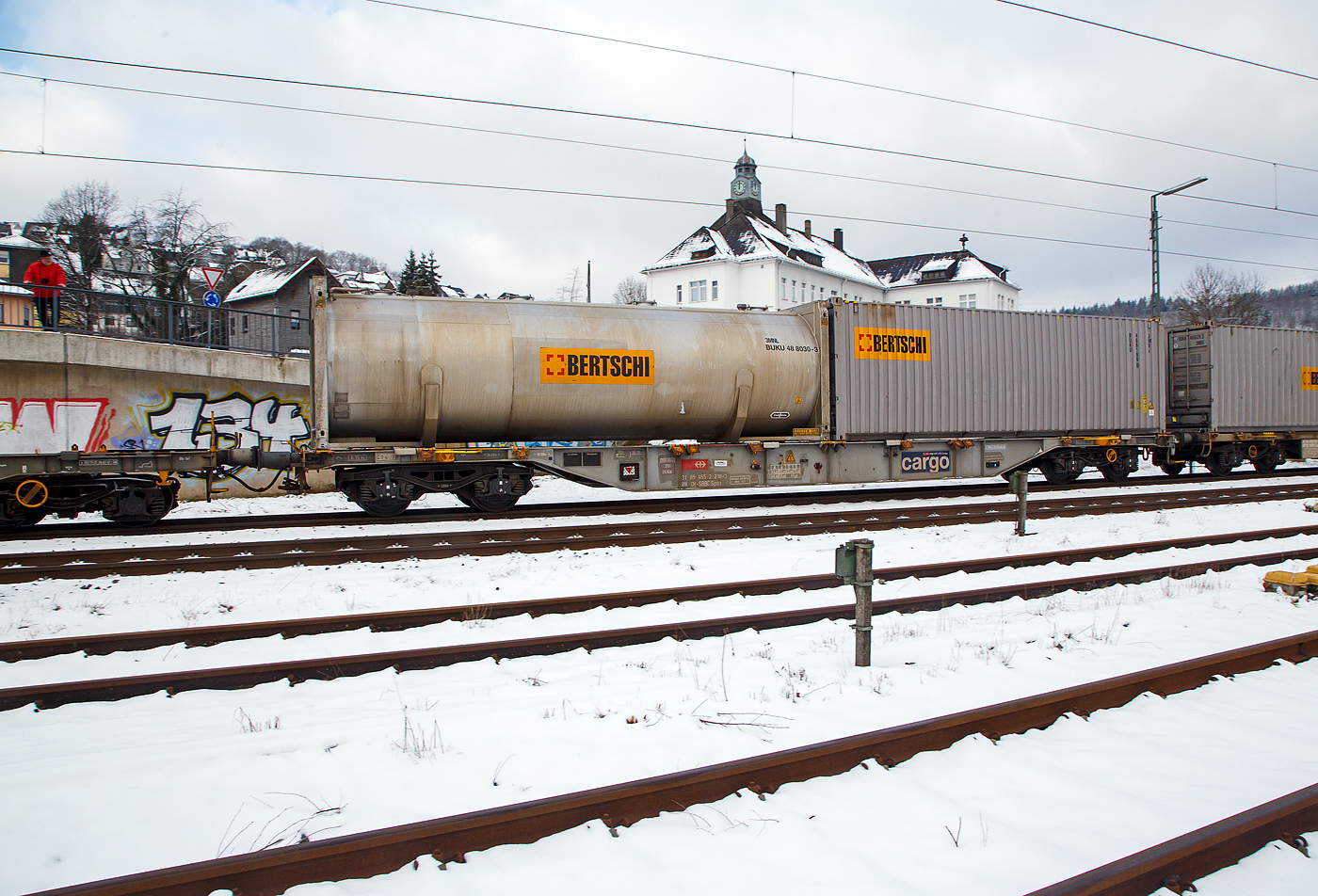 4-achsiger Drehgestell-Containertragwagen 31 85 4552 218-3 CH-SBBC, der Gattung Sgnss (60ft), der SBB Cargo AG, im Zugverband am 21.01.2023 bei der Zugdurchfahrt in Niederschelden (Sieg), beladen mit einem 30´ Tank-Containern und einem 30´ ISO-Containern von dem Logistikdienstleister Bertschi AG (D�rren�sch/Schweiz).

TECHNISCHE DATEN:
Spurweite: 1.435 mm
Anzahl der Achsen: 4 in zwei Drehgestellen
L�nge �ber Puffer: 19.990 mm
Drehzapfenabstand: 14.420 mm
Achsabstand im Drehgestell: 1.800mm
Laufraddurchmesser: 920 mm (neu)
Ladel�nge : 18.720 mm  (60 ft)
H�he der Ladeebene �ber SOK: 1.155 mm
H�chstgeschwindigkeit: 100 km/h Lastgrenze S / 120 km/h bei Lastgrenze SS und leer)
Max. Zuladung bei Lastgrenze S: 70,0 t (ab Streckenklasse D)
Max. Zuladung bei Lastgrenze SS: 60,0 t (ab Streckenklasse C)
Eigengewicht: 20.000 kg
Kleinster bef. Gleisbogenradius: R 75 m
Bauart der Bremse: DK-GP-A (K)
Bremssohle: Cosid 810
Intern. Verwendungsf�higkeit: RIV
Wageneinrichtungen: 36 Umklappbare Aufsetzzapfen
