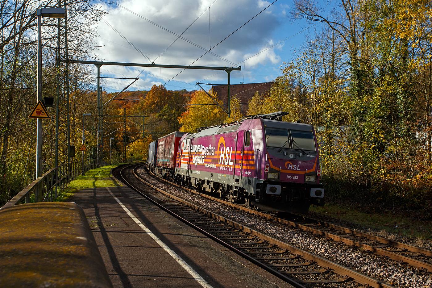 Als Schlussl�ufer, des von der TXL 7193 318 gezogenen KLV-Zugs, am 30 Oktober 2025 durch Scheuerfeld/Sieg in Richtung K�ln, die kalte an die HSL Logistik GmbH (Hamburg) vermietete 186 383-6 (91 80 6186 383-6 D-AKIEM) der AKIEM SAS. 

Die Bombardier TRAXX F140 MS2 wurde 2018 von Bombardier in Kassel unter der Fabriknummer 35415 gebaut. Die f�r 140 km/h zugelassene Multisystemlokomotive hat die Zulassungen/L�nderpaketen f�r Deutschland, �sterreich, die Niederlande und Belgien (D/A/NL/B). 