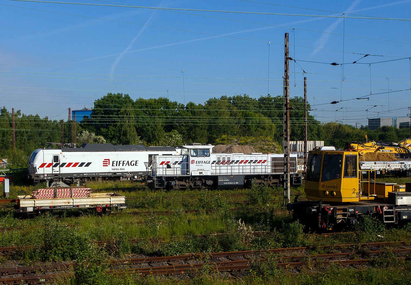 Blick am 20 Mai 2025 aus einem Zug auf den Abstellbereich (Schieneninfrastruktur) der Eiffage Infra-Rail GmbH in Herne (ehemals Heitkamp Rail GmbH): 
Vorne die an die Eiffage Infra-Rail vermietete 275 807-6 (92 80 1275 807-6 D-NRAIL), eine Vossloh G 1206 der der Northrail GmbH. Sie wurde 1999 von der Vossloh Locomotives GmbH in Kiel-Friedrichsort unter der Fabriknummer 1001016, als Mietlok der Vossloh, gebaut. Nach vielen Stationen ging sie 2024 an Northrail GmbH in Hamburg.

Hinten die SIEMENS Vectron Dual Mode 248 025-9 (90 80 2248 025-9 D-ERD) der Eiffage Infra-Rail. Die SIEMENS Vectron DM wurde 2022 von Siemens Mobility GmbH in München-Allach unter der Fabriknummer 23164 gebaut und im Januar 2023 an die Eiffage Infra-Rail geliefert.

Eiffage ist ein börsennotiertes französisches Bauunternehmen mit Firmensitz in Vélizy-Villacoublay. In Deutschland hat die Eiffage Infra-Rail GmbH ihren Sitz in Herne. Im Jahre 2010 übernahm Eiffage von Heijmans den Bereich Schieneninfrastruktur der ehemaligen Firma Heitkamp. Die Gleisbaugeräte und die zugehörige Werkstatt sind auf dem Gelände der ehemaligen Heitkamp Bauholding in Herne-Wanne beheimatet.