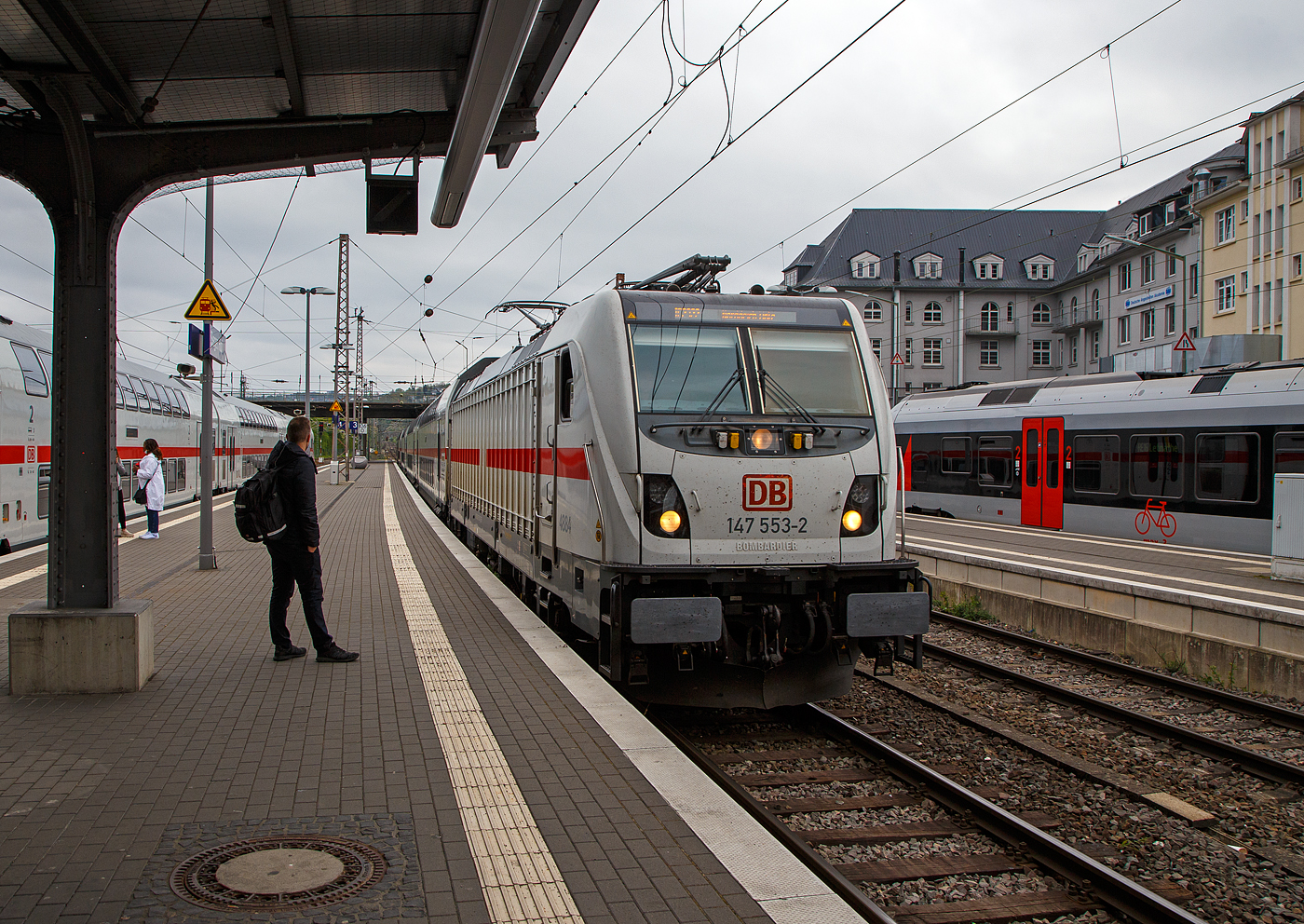 Da kommt unser IC nach Norddeich Mole....
Die 147 553-2 (91 80 6147 553-42 D-DB – IC 4884) der DB Fernverkehr AG f�hrt am 30.04.2022, mit dem IC 2322 (Frankfurt a.M. Hbf - Siegen - Hamm - M�nster - Norddeich Mole) in den Hauptbahnhof Siegen ein. Hier im Hbf Siegen macht der Zug Kopf, d.h. er wechselt die Fahrtrichtung und f�hrt gleich Steuerwagenvorraus Richtung Norddeich Mole weiter, daher wartet hier auch der neue Lokf�hrer. Dieser IC hat keine Freigabe f�r Nahverkehr Tickets.

Die TRAXX P160 AC3 wurde 2018 von Bombardier in Kassel unter der Fabriknummer 35444 gebaut und an die DB Fernverkehr AG geliefert. Sie hat die Zulassungen f�r Deutschland. F�r die Schweiz ist/war die Zulassung auch vorgesehen, daher hat sie auch vier Stromabnehmer (je 2 mit breiter Wippe und schmaler Wippe), doch wurde noch keine Zulassung f�r die Schweiz vom Hersteller erlangt.
