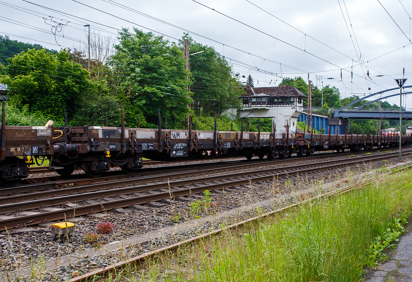 Der 4-achsiger Drehgestell-Flachwagen, mit Seiten-, Stirnwandklappen und Rungen, 31 80 3937 561-1 D-DB, der Gattung Res 687, der DB Cargo, am 03 Juni 2024 im Zugverband bei der Zugdurchfahrt in Kreuztal.

Insgesamt wurden 4.350 Wagen der Gattung Res 687 zwischen 1979 und 1985 für die DB gebaut. Hersteller waren u.a. MAN und die Waggon Union in Siegen und Berlin.

Mit einer Ladelänge von 18,50 m dienen diese Wagen zur Beförderung von schweren, langen Erzeugnissen der Eisen- und Stahlindustrie und Fertigbauteilen, Holz, Kleineisenzeug, Halbzeug, Steinen, Fahrzeugen u.a.m. Er besitzt keine klappbaren Ladeschwellen. Wegen seiner niedrigen Fußbodenhöhe können auch Container damit befördert werden. Vor den umlegbaren Stirnwänden sind je zwei absenkbare Rungen angeordnet. Der Wagen kann mit umgelegten Stirnwänden und abgesenkten Rungen gefahren werden. Die Höhe der umgelegten Stirnwandklappen über FO beträgt 38 mm. An den Längsseiten hat der Wagen je 8 Drehrungen und insgesamt 18 absenkbare Verzurreinrichtungen im Fußboden. Mit heruntergeklappten Seitenwänden kann der Wagen nur mit Lademaßüberschreitung befördert werden. Der Fußboden besteht aus Kiefernbohlen mit den Abmessungen 48 x 180 mm. Er kann eine Radlast von 5,0 t aufnehmen. Ein Teil der Wagen ist mit einer vom Boden aus bedienbaren Feststellbremse ausgerüstet.

TECHNISCHE DATEN:
Spurweite: 1.435 mm
Länge über Puffer: 19.900 mm
Drehzapfenabstand: 14.860 mm
Achsabstand im Drehgestell: 1.800 mm
Drehgestell-Bauart: Y 25 Cs (621.1)
Länge der Ladefläche: 18.500 mm
Ladebreite: 2.660 mm
Ladefläche: 49,0 m²
Laderaum: 25,5 m³
Rungenhöhe: 1.300 mm
Fußbodenhöhe über SOK: 1.238 mm
Höchstgeschwindigkeit: 100 km/h (beladen) / 120 km/h (leer)
Maximale Ladegewicht: 56,0 t (ab Streckenklasse C)
Eigengewicht: 23.700 kg
Bauart der Bremse: KE-GP (LL)
Bremssohle: IB 116
Kleinster bef. Gleisbogenradius: 35 m
Intern. Verwendungsfähigkeit: RIV

Die Bedeutung der Gattung Res:
R = Drehgestellflachwagen in Regelbauart
e = mit klappbaren Seitenwänden
s = zugelassen für Züge bis 100 km/h (beladen)
687 = Bauartnummer