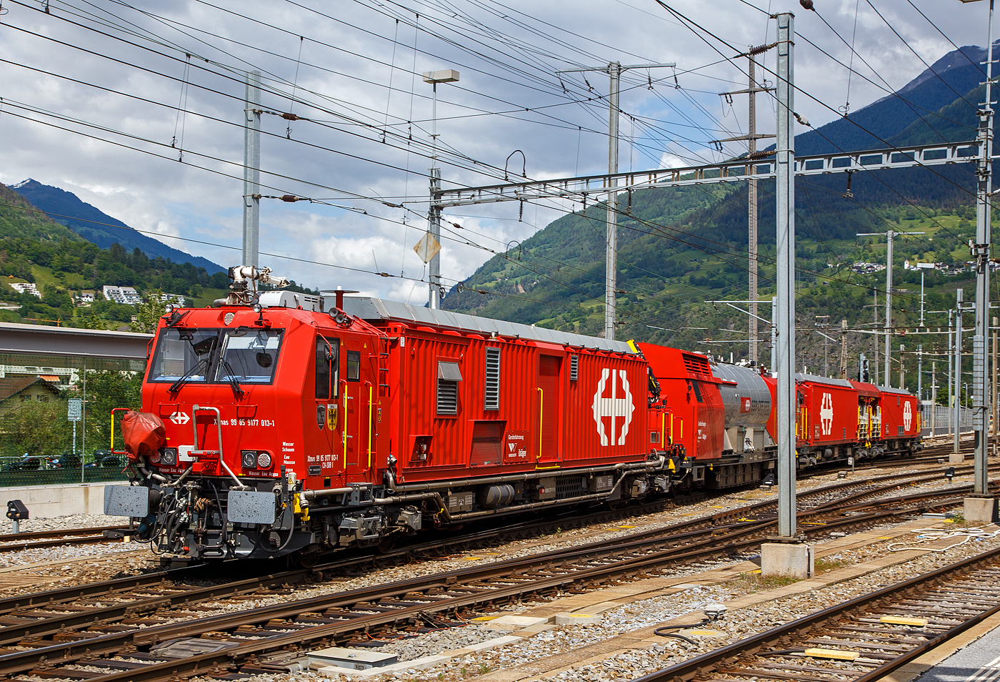 Der 4-teilige L�sch- und Rettungszug „Brig“ (ein vierteiliger LRZ 18) der SBB Infrastruktur erreicht am 25 Mai 2023 seinen Heimatbahnhof Brig.

Der L�sch- und Rettungszug wurde 2018 f�r die SBB Infrastruktur, Depot Brig, gebaut und besteht aus dem:
Rettungsfahrzeug 1 - Xtmas 99 85 9174 023-3 CH-SBBI;
Rettungsfahrzeug 2 - Xtmas 99 85 9174 013-4 CH-SBBI;
Tankl�schwagen - Xans 99 85 9375 013-1 CH-SBBI; sowie
Ger�tefahrzeug - Xtmas 99 85 9177 013-1 CH-SBBI

Die neuste Generation der L�sch- und Rettungsz�ge (LRZ 2018) ist vierteilig und besteht aus einem Tankl�schwagen, einem Ger�tefahrzeug und zwei Rettungsfahrzeugen. Der Antrieb erfolgt mit je zwei MTU-Dieselpowerpacks (6-Zylinder Turbo geladener Dieselmotor von MTU, Partikelfilter, Turbogetriebe mit eingebauten Retarder und K�hlsystem) nach EU-Abgas-Emissionsstufe IIIA Norm, mit je 390 kW Leistung �ber die beiden Rettungs- sowie das Ger�tefahrzeug. Der L�sch- und Rettungszug hat so eine installierte Gesamtleistung von 2.340 kW (6 x 390 kW), eine H�chstgeschwindigkeit von 100 km/h und kann Anh�ngelasten von 940 Tonnen bei einer Steigung von 27 Promille bewegen, in der Ebene sogar mit einem Gewicht von �ber 1.600 t. 

Der Tankl�schwagen ist nicht selbstfahrend, er ist als Steuerwagen ausgef�hrt, daher auch die Gattungsbezeichnung Xans. Er besitzt zwar einen Deutz 6-Zylinder- Dieselmotor (mit 238 KW Leistung) mit vollautomatischem Partikelfilter, einer und angeflanschtem Pumpenaggregat von Vogt, dieser wird aber nur Wasser- und Schaummittelpumpen ben�tigt.

Der gesamte Atemluftvorrat des Zuges betr�gt 1.980.000 Normliter und wird in 132 Speicherflaschen, die ein Volumen von 50 Litern haben, mit 300 Bar Druck gelagert. An verschiedenen Orten in den Innenr�umen und auf den Plattformen sind Anschl�sse f�r die Atemluftversorgung vorhanden. Daran k�nnen separate Atemschutzmasken oder das tragbare Atemschutzger�t mit Geber- und Nehmerschlauch angeschlossen werden. Alle F�hrerstandkabinen sind druckdicht und verf�gen �ber eine Atemluftversorgung, welche einen �berdruck erzeugt. In den F�hrerstandkabinen des Ger�tefahrzeugs und des Tankl�schwagens ist zus�tzlich ein Bedienpult f�r die Feuerl�schtechnik eingebaut.

Zwischen 4 und 5 Stunden  ist ein autonomer Betrieb des LRZ m�glich.

Im Einsatz wird der Zug in zwei Einheiten geteilt. Die erste Einheit aus Ger�tefahrzeug und Tankl�schwagen (mit 780 kW Antriebsleistung) dient der Feuerbek�mpfung und dem Bergungsarbeiten. Die zweite Einheit (mit 1.560 kW Antriebsleistung), bestehend aus zwei Rettungsfahrzeugen �bernimmt im Shuttleverkehr den Personentransport zu einem sicheren Ort.

Quellen: SBB und Anschriften
Stand (�berarbeitung): September 2025

