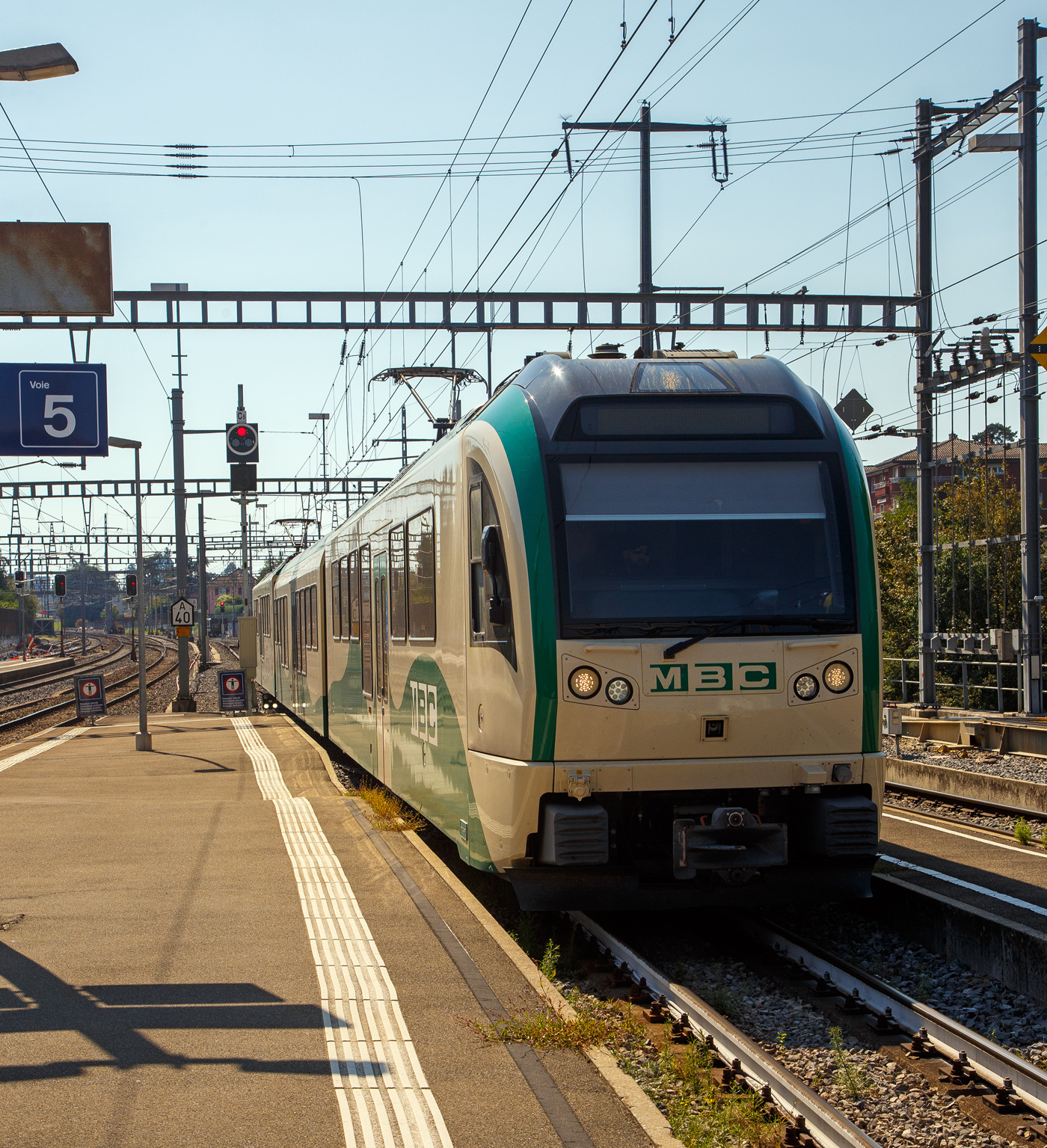 Der BAM/MBC dreiteilige elektrische Stadler Westschweizer Meterspurtriebzug, in der Komposition Be 4/4 38 + B4 2068+ Be 4/4 35, erreicht am 07 September 2023, als Regionalzug von Bière, den Bahnhof Morges.

Die MBC (ex BAM) hatte 2013 bei Stadler Rail 4 Fahrzeuge (dreiteilige elektrische Triebzüge Be4/4 + B + Be4/4) als Ersatz für bestehendes Rollmaterial bestellt, das das Ende seiner Lebensdauer erreicht hat. Mit dem neuen Rollmaterial konnte im Dezember 2015 der Halbstundentakt eingeführt werden. Damit wurde der Anschluss an die RE- und IR-Züge zwischen Lausanne und Genf geschaffen, die den Bahnhof von Morges im Halbstundentakt anfahren. Die Fahrzeuge mit modernem, dynamischem Design sind einladend und komfortabel. Sie entsprechen auch in technologischer Hinsicht den Betriebsbedingungen auf dieser Strecke und werden den hohen Erwartungen der Kunden gerecht. Gleichzeitig wurden Vereinfachungen bei der Instandhaltung ermöglicht. Den Fahrgästen stehen total 168 Sitzplätze zur Verfügung. Die Züge sind für eine Höchstgeschwindigkeit von 100 km/h ausgelegt.

Technische Merkmale:
• Wagenkasten aus Aluminium-Strangpressprofilen
• Luftgefederte Trieb- und Laufdrehgestelle
• Endtriebwagen können auch mit angepassten älteren Steuerwagen verkehren
• Multifunktionsabteile bei allen Einstiegen
• 3 Einstiegtüren pro Seite für schnellen Fahrgastwechsel
• Redundante Antriebsausrüstung bestehend aus 2 Antriebssträngen mit wassergekühlten IGBT-Stromrichtern
• Redundante Fahrzeugleittechnik mit Zugbus und Diagnoserechner

TECHNISCHE DATEN:
In der Komposition Be 4/4 + B + Be 4/4
Anzahl Fahrzeuge: 4 (Züge)
Hersteller: 	Stadler Bussnang AG
Baujahr: 2015
Einsatzgebiet: Morges – Apples – Bières – L’Isle
Spurweite: 1.000 mm (Meterspur)
Achsfolge: Bo‘Bo’ + 2’2’ + Bo‘Bo’
Länge über Kupplung: 60.310 mm (20.155 + 20.000 + 20.155 mm)
Fahrzeugbreite: 2.650 mm
Fahrzeughöhe: 4.020 mm
Achsabstand im Motordrehgestell: 2.000 mm
Achsabstand im Laufdrehgestell: 1.800 mm
Triebraddurchmesser:  810 mm (neu)
Laufraddurchmesser: 770 mm (neu)
Eigengewicht: 117 t
Höchstgeschwindigkeit: 100 km/h
Dauerleistung am Rad: 2 x 1.020 kW
Max. Leistung am Rad: 2 x 1.400 kW
Anfahrzugskraft: 300 kN
Anzahl der Fahrmotoren: 2 x 4
Anfahrbeschleunigung: 1.2 m/s²
Bremsleistung: 1.33 m/s²
Fahrleitungsspannung: 15.000 V, 16.7 Hz ~
Sitzplätze: 154 (2. Klasse) 
Klappsitze: 14
Stehplätze (bei 6 Pers./m²): 208
Fußbodenhöhe Niederflur am Einstieg: 380/ 480 mm
Fußbodenhöhe Hochflur: 1.000 /1.100 mm
Einstiegbreite: 1400 mm
Minimaler Kurvenradius: R 80 m (auf der Strecke)
Kupplungstyp: +GF+ 

Wie bei Stadler-Fahrzeugen üblich nimmt die Sitzanordnung auf die Fensterteilung Rücksicht, um den Fahrgästen einen ungehinderten Ausblicken zu ermöglichen. Die Fußbodenhöhe beträgt im Niederflurbereich einheitlich 480 mm. Im Türbereich senkt sie sich über eine Rampe auf 380 mm.

Allgemein:
Die STADLER Westschweizer Meterspurzüge aus den Jahren 2015/16 sind elektrische Niederflur-Triebzüge und -Triebwagen des Herstellers Stadler Rail, die bei sechs Westschweizer Privatbahnen (MBC / Travys / TPF / NStCM / MOB / CJ) mit unterschiedlichen Achsfolgen unter verschiedenen Stromsystemen im Einsatz stehen. Zudem erhielt die Appenzeller Bahnen (AB), die bekanntlich in der Deutschschweiz (Nordostschweiz) liegt, 2018 fünf ABe 4/12 die weitgehend den Meterspurzügen der TPF entsprechen.

Ausgangslage:
Für die vorhanden Pendelzüge Be 4/4 11–13 + Bt 51–53 aus dem Jahr 1981beschafften die Transports de la région Morges–Bière–Cossonay (MBC, ex BAM) bereits 2010 drei zu den vorhandenen Pendelzügen passende vierachsige Niederflurzwischenwagen B 2065–2067. Schon bei der Bestellung war vorgesehen, sie später mit passenden Triebwagen zu ergänzen, um komplett neue Züge zu erhalten. So bildeten diese den Ausgangspunkt für die Konstruktion.

2009 bestellte die Nyon-Saint-Cergue-Morez-Bahn (NStCM) bei Stadler vier zweiteilige Triebzüge ABe 4/8. Die NStCM hatte zunächst Interesse an Zügen in der Bauart der RBe 4/8 der Lausanne–Echallens–Bercher-Bahn. Der Kanton Waadt verweigerte jedoch die Finanzierung der Kleinserie und forderte aus Kostengründen eine gemeinsame Bestellung mit anderen Bahnen. Bei den Deutschschweizer Meterspurbahnen wusste man nichts von der Bestellung. Indessen verzeichneten mehrere Meterspurbahnen in der Romandie starke Nachfragesteigerungen, so dass der Kanton Waadt eine Kapazitätssteigerung und Erneuerung der auf seinem Gebiet verkehrenden Privatbahnen beschloss. Daraufhin schrieben die drei Waadtländer Meterspurbahnen MBC, Travys und Montreux-Berner Oberland-Bahn (MOB) zusammen mit den Transports publics fribourgeois (TPF) die Lieferung von 17 zwei- bzw. dreiteiligen Triebzügen aus. Trotz der Konkurrenz des Bombardier-Konzerns, der im waadtländischen Villeneuve ein Werk betreibt, erhielt Stadler Bussnang den Auftrag im Wert von 151 Millionen Franken. Damit hat der Thurgauer Hersteller bei den Schweizer Meterspurfahrzeugen seinen Konkurrenten aus dem Markt gedrängt, was ihm gute Preise bringen wird. Mit der gemeinsamen Bestellung ließen sich 28 Millionen Franken einsparen. Die NStCM schloss sich der Bestellung mit vier zweiteiligen Zügen im Wert von 66 Millionen an. Nachträglich bestellten die Chemins de fer du Jura (CJ) fünf Einteiler. Ursprünglich wollten die CJ komplette Triebzüge beschaffen, die bereitgestandenen Mittel hätten aber nur für drei Züge ausgereicht.

Die Anforderungen der Kunden sind unterschiedlich. MBC und Travys fahren mit 15.000 Volt Wechselstrom, die anderen Bahnen mit Gleichstrom. Die Strecken von MBC, Travys und MOB sind mit ihren starken Steigungen anspruchsvoll. Die MBC bestellten einen dreiteiligen und drei zweiteilige Züge, wobei die Zweiteiler mit den bereits vorhandenen Niederflurzwischenwagen zu Dreiteilern ergänzt wurden. Die Zugkraft ist so ausgelegt, dass sie für den Militärverkehr bis zu vier zusätzliche Personenwagen nach Bière befördern können. Mit den drei dreiteiligen Zügen stehen Travys zusammen mit den beiden GTW ABe 2/6 modernes Rollmaterial für die Strecke Yverdon–Ste-Croix (YSteC) zur Verfügung. Die vier leistungsstarken Zweiteiler der MOB werden wie die Allegra der Rhätischen Bahn (RhB) zur Traktion von längeren Zügen mit bis zu neun Reisezugwagen eingesetzt. Die TPF nutzen die neuen Fahrzeuge, um auf ihrem Schmalspurnetz die erste Wagenklasse einzuführen. Die als Dreiteiler abgelieferten Züge können zur Anpassung an die Verkehrsnachfrage als zwei- und vierteilige Kompositionen formiert werden. Sie lösten die BDe 4/4 und Be 4/4 aus den 1970er-Jahren ab, die nun den ausgeprägten Schülerverkehrs abdecken. Mit ihren Be 4/4 651–655 sowie fünf modernisierten Steuerwagen ABt 711–715 aus den Jahren 1985/86 und drei Mittelwagen können die CJ den Regelverkehr seit 2016 mit behindertengerechten Kompositionen abdecken. Sie verkehren vorerst auf der Strecke Tavannes–Le Noirmont. 

Die MBC und MOB vereinbarten Optionen über je eine zusätzliche Komposition, die TPF über vier und die NStCM über fünf, wobei die Bestellung der NStCM für das Jahr 2018 geplant war. Im Dezember 2019 bestellte die NStCM sechs weitere Züge, die 2022 abgeliefert wurden. sollten. Wie erst im Dezember 2022 bekannt wurde, bestellte die TPF im Jahr 2020 drei weitere Züge und im Juni 2021 noch einen zusätzlicher Zug bestehend aus ABe 2/4 – B – Be 2/4 mit den Nummern 107–110 bei Stadler. Die Lieferung der ersten drei Züge soll im November 2023 erfolgen, der vierte Zug im Februar 2024.

Quelle: Anschriften am Fahrzeug und Wikipedia
