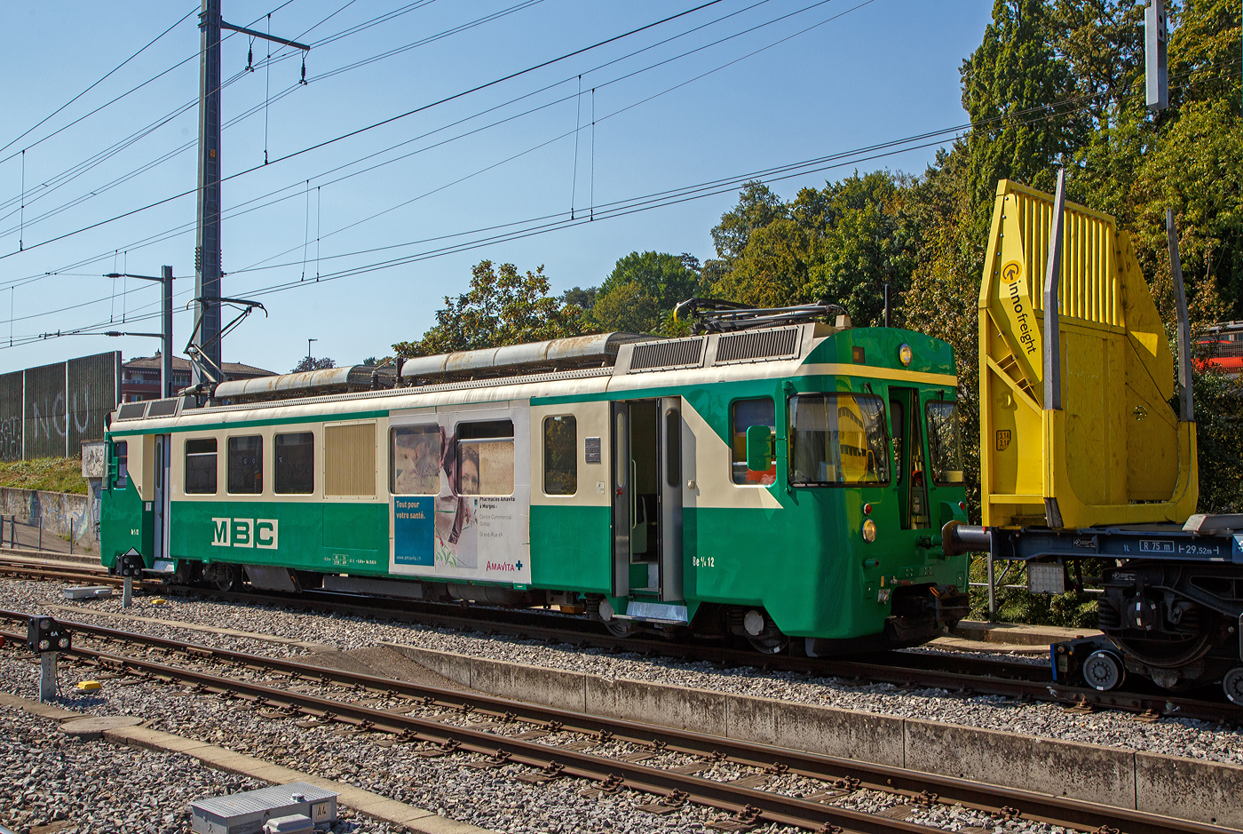 Der elektrische Schmalspur Güterzug-/Personentriebwagen MBC/BAM Be 4/4 12 rangiert, am 07 September 2023 an einer Rollbockgrube beim Bahnhof Morges, den leeren 2 x vierachsiger Flachwagen in Sonderbauart (INNOFREIGHT Holz-Doppelwagen) 37 80 4657 028-9 D-VTG der Gattung Sggmrrs S240, auf schmalspurige Rollböcke vom Typ Vevey.

Die Be 4/4 Triebwagen:
Im Jahre 1978 bestellten die BAM und die YSteC je drei Triebwagen Be 4/4 11–13 bzw. 1–3. 1980 konnte die Bestellung um fünf passende Steuerwagen Bt 51–53 (BAM) und 51–52 (YSteC) ergänzt werden. Die Be 4/4 sind sechs meterspurige vierachsige Elektrotriebwagen, die 1981 von den Ateliers de constructions mécaniques de Vevey (ACMV) an die Chemin de fer Bière–Apples–Morges (BAM) und Chemin de fer Yverdon–Ste-Croix (YSteC) geliefert wurden. Die Drehgestelle wurden von SIG und die Elektrik von SAAS (Société Anonyme des Ateliers de Sécheron) der ACMV zugeliefert. Wegen der Übernahme der Sécheron-Werke durch die BBC wurde die elektrische Ausrüstung jedoch in Oerlikon montiert. Die Steuerwagen wurden 1982 ausgeliefert.

Mit ihrer Leistung von 780 kW und einem Dienstgewicht von 44 Tonnen sind sie auch zur Beförderung schwerer Rollbock-Züge geeignet. Die zulässige Anhängelast beträgt 200 Tonnen auf 35 ‰ Steigung. 

Die BAM Triebwagen besitzen  +GF+-Kupplungen, die das selbsttätige Kuppeln auch in den Kurven ermöglichen. Hier für die Rollbock-Züge besitzen die Triebwagen eine spezielle Kuppelstange. 

Die BAM änderte 2003 ihren Namen in Transports de la région Morges–Bière–Cossonay (MBC).

TECHNISCHE DATEN:
Hersteller:  ACMV, SIG, SAAS
Baujahr: 1981
Spurweite: 1.000 mm (Meterspur)
Achsfolge: Bo' Bo'
Länge über Puffer: 18.750 mm
Drehzapfenabstand: 12.480 mm
Treibraddurchmesser:  750 mm (neu)
Höhe: 4.100 mm
Breit: 2.650 mm
Dienstgewicht: 46 t
Höchstgeschwindigkeit: 75 km/h
Leistung: 780 kW
Anzahl der Fahrmotoren: 4
Fahrleitungsspannung: 15.000 V, 16.7 Hz ~
Sitzplätze: 40 (2. Klasse)
Steuerung: Vielfachsteuerung
Kupplungstyp: +GF+ bei BAM (bei der YSteC Mittelpuffer Zp2) 

Der Güterverkehr der BAM:
Bei der Betriebseröffnung besaß die BAM rund ein Dutzend schmalspurige Güterwagen, eigentlich recht wenig. Obwohl die Trassierung problemlos den Rollschemelbetrieb erlaubt, wurde dieser erst 1965 eingeführt. 1981 ging die BAM zum zum Rollbock-System Vevey über, hierbei wird die Achse des Normalspurwagens nicht mehr fixiert. Der Wagen steht mit seinen Rädern in speziell geformten Mulden. Derartige Rollböcke – als System Vevey von den Ateliers de constructions mécaniques de Vevey (ACMV) in Serie gefertigt – werden bei mehreren Bahnen in der Schweiz und einer Bahn in Deutschland eingesetzt. Der Hauptunterschied zum klassischen Rollbock ist, dass das Aufbocken bei langsamer Fahrt automatisch geschieht. Somit sind zahlreiche Unannehmlichkeiten und Gefährdungspotenziale behoben. Zudem konnten damit bei der BAM auch die etwas höheren Panzer 87 (Leopard 2) transportiert werden.

Die schmalspurigen Güterwagen wurden veräußert oder zum großen Teil bereits 1976 bis 1978 abgebrochen. Seit den 1990er Jahren wird der Güterverkehr fast ausschließlich mit Normalspurwagen abgewickelt. Zu Beginn der 2010er Jahre transportierte die BAM jährlich rund 40 000 Tonnen Güter, vorwiegend Armeepanzer, Zuckerrüben und Getreide. Im Herbst 2013 nahm sie den Transport von etwa 170 000 Tonnen Kies pro Jahr aus Apples nach Morges und weiter auf der SBB-Strecke nach Gland auf. Um die Kiesgrube auszufüllen, befördert die MBC in der Gegenrichtung 100 000 Tonnen Aushubmaterial. 


Im Jahre 1978 bestellten die BAM und die YSteC je drei Triebwagen Be 4/4 11–13 bzw. 1–3. 1980 konnte die Bestellung um fünf passende Steuerwagen Bt 51–53 (BAM) und 51–52 (YSteC) ergänzt werden. Die Be 4/4 sind sechs meterspurige vierachsige Elektrotriebwagen, die 1981 von den Ateliers de constructions mécaniques de Vevey (ACMV) an die Chemin de fer Bière–Apples–Morges (BAM) und Chemin de fer Yverdon–Ste-Croix (YSteC) geliefert wurden. Die Drehgestelle wurden von SIG und die Elektrik von SAAS (Société Anonyme des Ateliers de Sécheron) der ACMV zugeliefert. Wegen der Übernahme der Sécheron-Werke durch die BBC wurde die elektrische Ausrüstung jedoch in Oerlikon montiert. Die Steuerwagen wurden 1982 ausgeliefert.

Mit ihrer Leistung von 780 kW und einem Dienstgewicht von 44 Tonnen sind sie auch zur Beförderung schwerer Rollbock-Züge geeignet. Die zulässige Anhängelast beträgt 200 Tonnen auf 35 ‰ Steigung. 

Die BAM Triebwagen besitzen  +GF+-Kupplungen, die das selbsttätige Kuppeln auch in den Kurven ermöglichen. Hier für die Rollbock-Züge besitzen die Triebwagen eine spezielle Kuppelstange. 

Die BAM änderte 2003 ihren Namen in Transports de la région Morges–Bière–Cossonay (MBC).