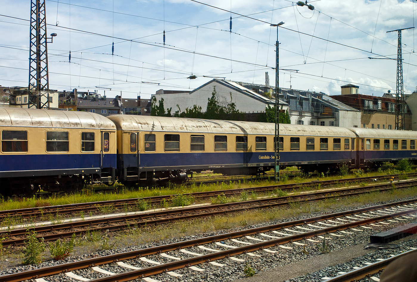 Der erste Klasse Reisezugwagen (Abteilwagen) D-CBB 56 80 10-40 124-4 der Gattung Am 208 der Centralbahn GmbH (Mönchengladbach), eingereiht im Zugverband eines mit 12 Wagen sehr langen Sonder- oder Partyzug der CBB, am 16 Mai 2024 in Köln-West, aufgenommen aus einen Zug heraus.

Der UIC-X-Wagen wurde 1957 von der Waggonfabrik Wegmann & Co. in Kassel gebaut und als DB 11 924 Esn der Gattung A4ümg-54 an die Deutschen Bundesbahn (DB) geliefert. 1966 erfolgte der Umbau und Umzeichnung in D-DB 51 80 10-40 112-4 der Gattung Am 202, im Jahr 1984 wurde er bei Wegmann zum D-DB 51 80 03-40 124-8 Am 036 umgebaut. Im Jahr 1993 wurde er an den EK-Verlag verkauft, 2000ter ging er als D-CBB 56 80 10-40 124-4 Am 208 an die Centralbahn.

Die Wagen der Gattung Am 208 bieten 60 bequeme Sitzplätze in zehn 6er-Abteilen der 1. Wagenklasse, zudem besitzen sie 2 WC/ Waschräume. Dieser Wagen ist für 140 km/h zugelassen und mehrspannungsfähig.

Schnellzugwagen A4ümg-54 DB
Das Bundesbahn-Zentral-Amt (BZA) Minden der Deutschen Bundesbahn (DB) entwickelte um 1952 ein Typenprogramm für 26,4 m-Fernreisezugwagen (Gruppe-53). Unter der Leitung von Dr.-Ing. Adolf Mielich entstand ein als Baukastensystem ausgelegtes Wagen-Programm. Er griff seine Entwürfe aus der Reichsbahnzeit wieder auf, zudem viele moderne Elemente wie die geschlossenen Gummiwulstübergänge und 1.000 bzw. 1.200 mm breite Übersetzfenster. Von den Vorkriegswagentypen unterschied es sich durch gerade Abteilanzahlen und symmetrische Wagenhälften, welche es ermöglichten, gleiche oder unterschiedliche Wagenklassen sowie Speise- und Packräume miteinander zu kombinieren. Nach neun Probewagen im Jahr 1952 begann 1955 die Serienfertigung. Die B4ümg-54 Reisezugwagen (1.225 Stück) boten den Reisenden der 2. Klasse erstmals nur drei Sitze pro Bank, statt bisher vier. Diese Komfortverbesserung bei dem „Reisezugwagen fürs Volk“ kam bei den Fahrgästen sehr gut an. Die erstklassige Wagenbauart A4ümg-54 (199 Stück) unterstrich beispielhaft den gestiegenen Reisekomfort jener Zeit. In eleganter, dunkelblauer Lackierung verließen die Wagen die Werke und wurden vorrangig in die F-Zugverbände der DB eingereiht. Vervollständigt wurde die Wagengruppe-53 durch die gemischt-klassigen AB4ümg-55 (357 Stück) und ab dem Ende der 1950er-Jahre durch die Halbgepäckwagen der Bauart BPw4üm-58/59 (138 Stück). Durch ihre wegweisenden Neuerungen waren die Wagen, und die aus Ihnen abgeleiteten späteren Umbauten, für die kommenden Jahrzehnte nicht aus den Reisezügen der DB wegzudenken. So verwundert es nicht, dass die letzten Wagen teilweise erst zu Beginn in den 1990er-Jahre ausgemustert wurden, oder dann ein zweites Leben im Museumsverkehr begannen.

TECHNISCHE DATEN:
Spurweite: 1.435 mm (Normalspur)
Länge über Puffer: 26.400 mm
Wagenkastenlänge: 26.100 mm
Wagenkastenbreite: 2.850  mm
Höhe über Schienenoberkante: 4.050 mm
Drehzapfenabstand: 19.000 mm
Achsstand im Drehgestell: 2.500 mm
Drehgestellbauart: Minden-Deutz 330
Leergewicht: 37 t
Höchstgeschwindigkeit: 140 km/h
Sitzplätze in der 1. Klasse: 60
Abteile: 10
Toiletten/Waschraum: 2 
Bremsbauart: KE-GPR
Energieversorgung: Achsgenerator

Die Centralbahn GmbH (Mönchengladbach) gehört zur Centralbahn AG mit Sitz in Basel. Hauptgeschäft ist die Durchführung von Sonderzugfahrten mit eigenen Fahrzeugen.