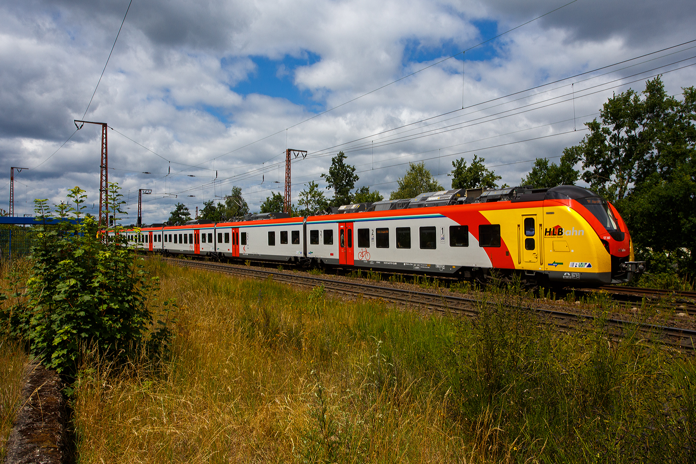 Der ET 267 (1440 267 / 1441 267 / 1841 267 / 1441 767 und 1440 767), ein fünfteiliger Niederflur-Elektrotriebwagen vom Typ Alstom CORADIA Continental 2 (XCC MHX) der HLB (Hessische Landesbahn GmbH), rauscht am 11 Juli 2025, als RE 99 „Main-Sieg-Express“ (Frankfurt/Main - Gießen - Siegen) Umlauf HLB24512, durch Wilnsdorf-Rudersdorf (Kreis Siegen) in Richtung Siegen. 

Der Elektrotriebzug wurden 2023 von der Alstom Transport Deutschland GmbH (vormals LHB) in Salzgitter-Watenstedt unter der Fabriknummer D041545-014 gebaut und an die HLB geliefert. Die Coradia Continental benötigten wegen einer neuen Steuerungssoftware eine neue Zulassung, nach Problemen mit dieser, hatte ALSTOM erst Ende April 2024 die Zulassung für die neuen Coradia Continental für die Hessische Landesbahn (HLB) erhalten und so erfolgte die Abnahme erst zum 30. April 2024.