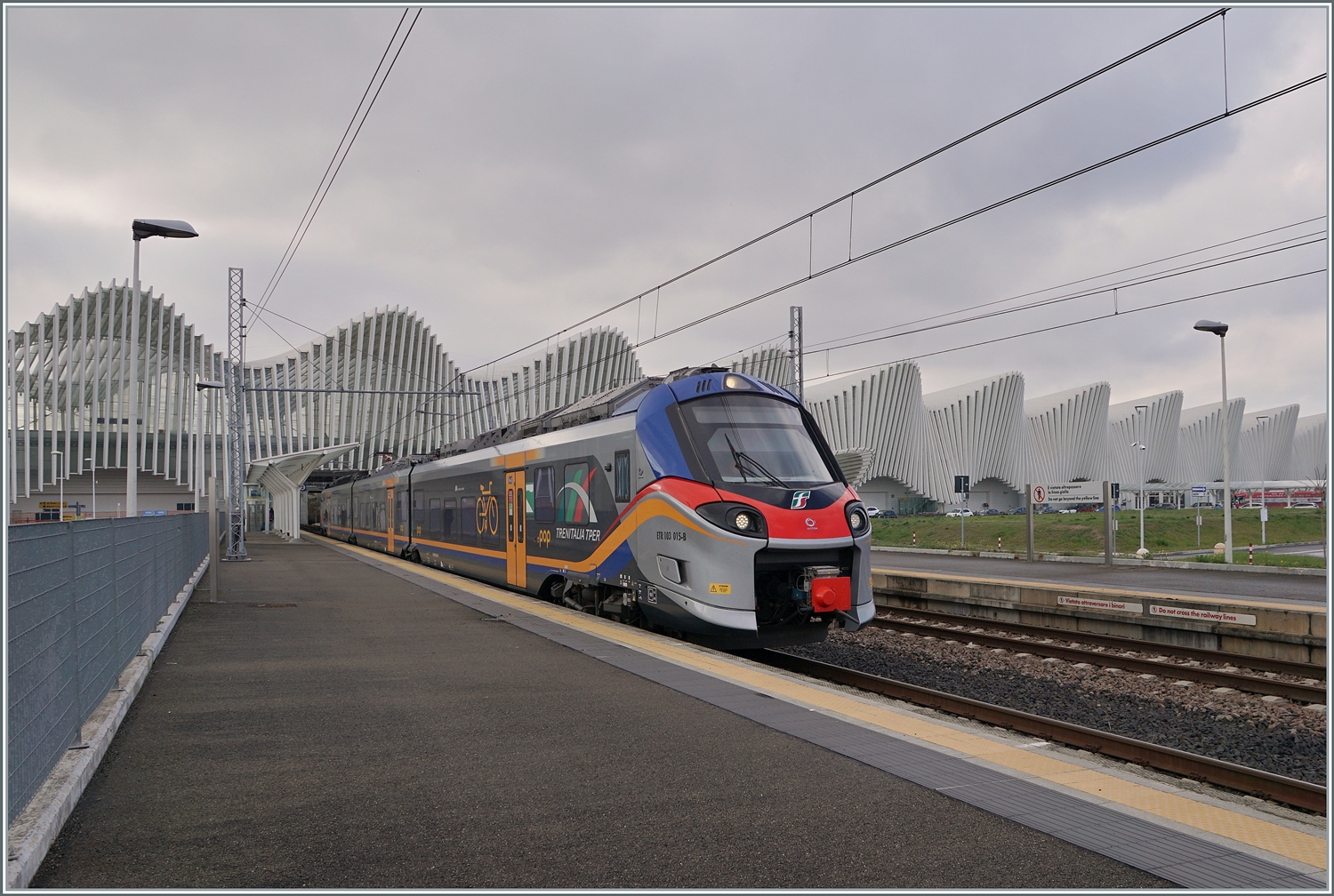 Der FS Treniatalia ETR 103-015 der Tochtergesellschaft TPER (Transporto Passeggeri Emilia Romagna) ist als Regionalzug 90176 von Reggio S. Lazzaro nach Guastalla unterwegs und verlässt den Bahnhof Reggio Mediopadana. Im Hintergrund ist der imposante Bahnhof von Reggio Emilia AV zu erkennen. 

14. März 2023