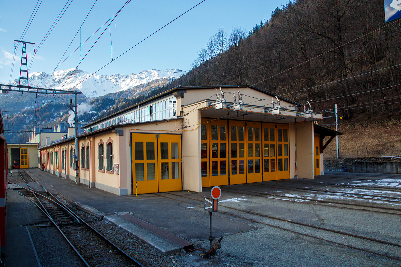Der Lokschuppen, Depot und Werkstätte der Rhätischen Bahn / Ferrovia retica (RhB) in Poschiavo am 20 Februar 2017.

Der Bahnhof Poschiavo wurde auf Wunsch der Gemeinde etwas außerhalb des Ortes errichtet. Für die 1908 eröffnete Berninabahn bedeutet Poschiavo den wichtigsten Bahnhof südlich des Passes.Er besitzt eine Betriebswerkstätte, in der auch einige historische Fahrzeuge der Berninabahn stationiert sind. Im Depot mit angegliederter Werkstätte werden die Gleichstrom-Triebfahrzeuge der Rhätischen Bahn gewartet. Der Stützpunkt des Bahndienstes mit Fahrleitungsdienst betreut die gesamte etwa 60 km lange Bahnlinie. Im Jahre 1962 wurde das Stationsgebäude neu erbaut, von 1969 bis 1972 das Depot erweitert. 