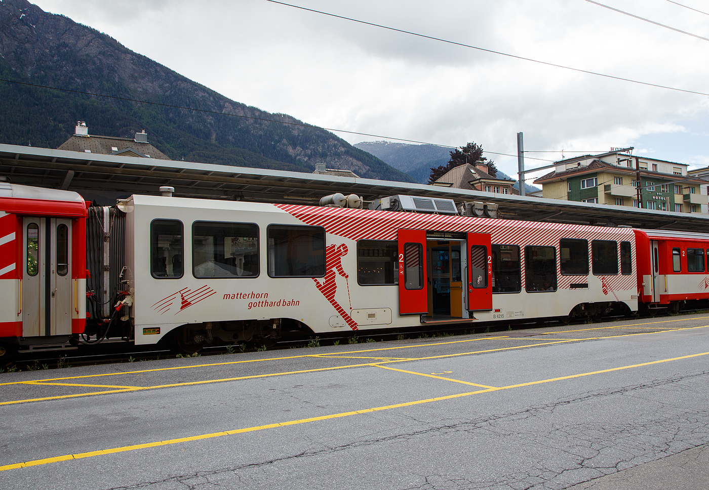 Der MGB 2. Klasse STADLER Niederflur-Zwischenwagen B 4215 am 25.05.2023 im Bahnhof Brig (Vorplatz) im Zugverband.

Stadler baute 2013 f�r die Matterhorn-Gotthard-Bahn elf dieser klimatisierten Niederflurwagen B 4211 bis 4221, mit denen die Regionalz�ge behindertengerecht gemacht wurden. Die neuen Wagen sind am wei�en Anstrich mit Wintersportmotiven zu erkennen.

TECHNISCHE DATEN:
Spurweite: 1.000 mm
L�nge �ber Puffer 18.280 mm
Drehzapfenabstand: 12.830 mm
Achsabstand im Drehgestell: 1.800 mm
Laufraddurchmesser: 685 mm (neu) / 635 mm (abgenutzt)
L�nge Wagenkasten: 17.480 mm
Breite Wagenkasten: 2.650 mm
H�he �ber SOK: 3.780 mm
Eigengewicht: 17,9 t
Einstiegsh�he (Schiebetritt): 380 mm
Fu�bodenh�he: 440 mm (NF) / 940 mm (HF) 
Lichte Einstiegsbreite: 1.600 mm 
Sitzpl�tze: 48 und 7 Klappsitze in der 2. Klasse (37 Stehpl�tze)
Zul. H�chstgeschwindigkeit: 90 km/h
Zugelassen f�r Netz der: MGB