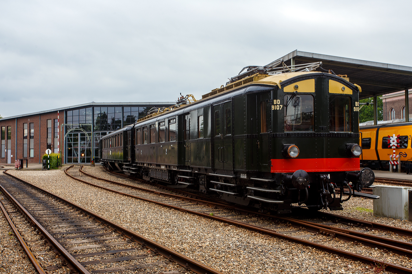 Der NS Mat ’24-Triebwagenzug (BD 9107, C 8553 und C 8104) „Blokkendozen“ (Kastendose) am 24 Juni 2025 im Het Spoorwegmuseum (bis 2005 NSM - Nederlands Spoorwegmuseum / Niederländischen Eisenbahnmuseum) in Utrecht im ehemaligen Bahnhof Maliebaanstation. Ein Eisenbahnmuseum das zum Verweilen einlädt. Hier im Vordergrund der Steuerwagen NS C 8104 (Ces) mit 88 Sitzplätzen der 3. Klasse und Durchgangsmöglichkeit, ex Triebwagen NS C 9411 (mCv).

Die NS-Baureihe Mat ’24 oder Materieel ’24 war eine (die erste) Serie von Elektrotriebzügen, die von der NS - Nederlandse Spoorwegen (Niederländischen Staatsbahnen, heute Niederländische Eisenbahnen AG) ab 1924 in großer Zahl eingesetzt wurde. Diese Züge sind unglaublich robust und schwer. nd der Tatsache, dass die Trainer wie Bausteine zusammengestellt werden können. Im Volksmund erhielten sie wegen des eckigen Äußeren und der Tatsache, dass die Wagen wie Bausteine zusammengestellt werden konnten, den Spitznamen „Blokkendozen“ (Kastendose). Ein weiterer Spitzname war „buffermaterieel“, weil sie im Unterschied zu anderen, mehr windschlüpfig aussehenden elektrischen Triebzügen mit üblicher Schraubenkupplung versehen waren. Wegen der Verbindung über Schraubenkupplung mit zwei Puffern konnten die Einheiten sehr flexibel kombiniert werden. Meist bestand ein Zug aus zwei Triebwagen und zwei oder drei antriebslosen Mittelwagen. Die lauten Geräusche der Motoren und Antriebe erinnerten manche Fahrgäste an Staubsauger, so dass auch dieser weitere Spitzname  Staubsauger  verwendet wurde. 

Ab Mitte der 1950er Jahre wurden die Mat ’24 zunehmend durch die neue Baureihe Mat ’54 ersetzt. Bei einigen Triebwagen wurden die Stromabnehmer und Motoren demontiert, sie wurden als einfache Beiwagen weiterverwendet. Da die Mat ’24 sehr robust waren, wurden einige Einheiten später auch als Postwagen oder für Dienstzwecke eingesetzt. Mehrere Wagen blieben museal erhalten.

Der Steuerwagen C 8104:
Der Steuerwagen C 8104 (Ces) wurde ursprünglich als Elektrotriebwagen C 9411 (mCv) 1928 bei NV Werkspoor in Zuilen mit einer elektrischen Installation von Heemaf in Hengelo gebaut. Er verfügte über 88 Sitzplätze der 3. Klasse und war als Spitzenverstärkung für die Hauptstrecke Amsterdam – Rotterdam vorgesehen. Durch einen Brand schwer beschädigt, wurde er 1944 zur Reparatur an Werkspoor gegeben, das inzwischen Teil der Gemeinde Utrecht geworden war. Erst nach dem Krieg im Jahr 1946 wurde C 9411 wieder in Dienst gestellt.

Der C 9411 war 1956 der erste Mat ’24-Triebwagen (Blokkendozen- Motorwagen) der in einen gezogenen Personenwagen, für den Einsatz hinter Elektrolokomotiven, umgebaut wurde und hauptsächlich als Spitzenverstärkung auf längeren Strecken innerhalb der Niederlande dienen sollte. Es erhielt daraufhin die Nummer B 5841 (Bz), wobei die 88 Sitzplätze auf Holzbänken unverändert blieben. Eine Einschränkung des Einsatzes war das Fehlen einer Toilette.

Aufgrund der Verfügbarkeit neuer und besserer Ausrüstung wurde der nunmehrige B 5841 im Jahr 1973 überflüssig. Anschließend wurde er zum Ausstellungswagen 99-31 003 umgebaut. Als solcher wurde er bis 1982 verwendet und dann für Museumszwecke reserviert.

Im Jahr 1983 begann man mit einer behutsamen Restaurierung, bei der zunächst die Innenausstattung mit Bänken und Türen eines zuvor abgerissenen „Blokkendozen“-Wagens (Kastendose-Wagens) wiederhergestellt wurde. Er erhielt erneut 88 Sitzplätze auf Holzbänken. Auch der voll ausgestattete Steuerstand wurde umgebaut. In den Jahren 1987 – 1989 erfolgte eine Generalüberholung und erhielt nun die Nummer C 8104 (Ces), da er nun mit den ursprünglichen Steuerwagen C 8101 – 8103 (Ces) identisch war. Der einzige Unterschied zwischen mCv und Ces besteht im Fehlen von Fahrmotoren und der dazugehörigen Elektroinstallation beim Ces.

Abkürzungen:
C = 3. Klasse
e = elektrischer Zwischenwagen
m = Triebwagen
s = ausgestattet mit Steuerstand
v = ausgestattet mit Steuerstand mit Balgdurchgang
z = ohne Toilette

Der dreiteilige Zug von Mat’24 des Niederländischen Eisenbahnmuseums, bestehend aus BD 9107, C 8553 und C 8104, war aufgrund einer Überholung des C 8104 und dem Fehlen der seit dem 1. April 2009 vorgeschriebenen automatischen Zugbeeinflussung ATB vorübergehend außer Betrieb. Die Überholung der Drehgestelle des C 8104 fand 2009 statt. Der Einbau der vereinfachten Version der ATB (ATBe) und deren Abnahme erfolgten im Mai und Juni 2010 bei Strukton in Zutphen. Im September wurde die Einsatzbescheinigung ausgestellt, danach fand am 9. Oktober wieder die erste Fahrt für ehrenamtliche Helfer des Eisenbahnmuseums statt.

Aufgrund größerer Wartungsarbeiten ist der Kastendosenzug aber z.Z. vorübergehend außer Betrieb.

TECHNISCHE DATEN:
Hersteller:	Werkspoor NV, Zuilen
Baujahr:1928
Typ:	Mat'24 ursprünglich '28 mC / seit 1989 Ces, Serie C 8101 – 8103 (8104)
Historischen Nummer:	ab 1928 - C 9411 / ab 1956 - B 5841 / ab 1973 - 99-31 003 / seit 1989 - C 8104
Spurweite:	1.435 mm (Normalspur)
Achsfolge:	2'2' (4 Achsen in zwei Drehgestellen)
Gewicht: 39 t
Länge über die Puffer:	19.800 mm
Höchstgeschwindigkeit: 120 km/h
Kupplung: Schraubenkupplung (UIC-Kupplung)
Betriebsfähigkeit: ja
