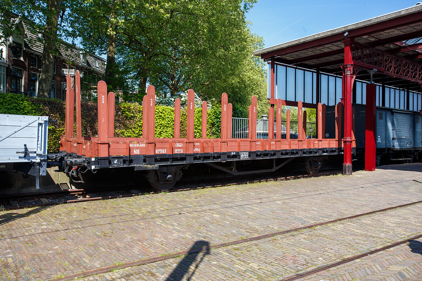 Der NS Rungenwagen LWGK 87583 am 29 April 2025 im Het Spoorwegmuseum (bis 2005 NSM - Nederlands Spoorwegmuseum / Niederl�ndischen Eisenbahnmuseum) in Utrecht im Bahnhof Maliebaan.

Zwischen 1926 und 1930 stellten die NS- Niederl�ndischen Eisenbahnen 100 zweiachsige 14 m langn Rungenwagen in Dienst. Diese Wagen waren im Wesentlichen eine Fortsetzung der alten Bauweise. Als Verbesserung war es nun jedoch m�glich, die Seitenw�nde abschnittsweise zu entfernen. Der obere Teil bestand also aus zehn 40 cm hohen Bordw�nden. Als alle Bordw�nde und Rungen entfernt worden waren, blieb ein flacher Wagen �brig, der sich ideal f�r den Milit�rtransport eignete. Die Rungen hatten eine L�nge von 2,50 m. Ab 1938 wurden die, oben rechteckig und mit Binderingen versehenen, urspr�nglichen Rungen, durch die bekannteren runden Rungen ersetzt. Die Wagen blieben bis in die 1980er Jahre im Einsatz. Mehrere Exemplare sind noch erhalten geblieben.

Dieser Wagen wurde 1930 von Werkspoor N.V. in Zuilen (heute Stadtteil von Utrecht) gebaut und als 87583 LWGK gef�hrt, ab 1967 wurde er zum 21 84 302 4 044-8 Kb und wechselte sp�ter noch mehrmals die Nummern. 

TECHNISCHE DATEN:
Spurweite: 1.435 mm (Normalspur)
Anzahl der Achsen: 2
L�nge �ber Puffer: 14.320 mm
Achsabstand: 8.000 mm
L�nge der Ladefl�che: 13.000 mm
Ladefl�che: 35,8 m�
Leergewicht: 11.870 kg
Max. Zuladung: 17,5 t
H�chstgeschwindigkeit: 80 km/h
Bremse: Kr-G
