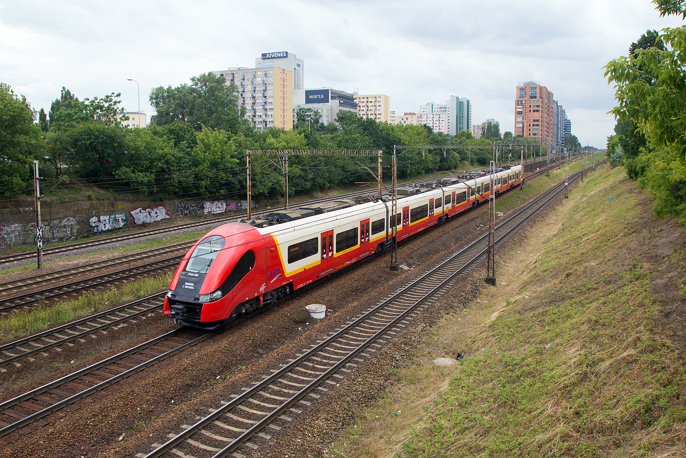Der sechsteilige Pesa Elf - 27WE-008 (2 160 048-6) der SKMWA (Szybka Kolej Miejska w Warszawie, deutsch Stadtschnellbahn Warschau) erreicht am 26.06.2017 als S 3 bald den Bahnhof Warszawa Ochota (in Warschau). 

Die Pesa Elf (Eelectric low floor) sind 3000 V DC elektrische Niederflur-Triebzüge, welche von der Pojazdy Szynowe Pesa Bydgoszcz SA (Pesa; deutsch Schienenfahrzeuge Bromberg AG) entwickelt und gebaut wurden. Hier die 27WE sind sechsteilige elektrische Triebzüge, sie sind die längsten Fahrzeuge der Plattform ELF des Herstellers.

Im Jahr 2013 lieferte Pesa in Bydgoszcz (Bromberg) 13 sechsteilige Triebzüge des Typs 27WE an die SKM Warschau. Die Fahrzeuge sind ähnlich der vierteiligen Züge der Plattform ELF aufgebaut. Durch den Einsatz wurde die Fahrzeugsituation auf der SKM spürbar verbessert, sodass es zur Ausmusterung von Altbaufahrzeugen kommen konnte.

Konstruktion:
Die Produktfamilie orientiert sich an vorhandene Konstruktionen wie dem Siemens Desiro, Alstom Coradia Continental oder Bombardier Talent 2. Merkmal ist die Verwendung als niederfluriges Fahrzeug bei S-Bahnen bis hin zum Schnellzug mit der entsprechenden Anzahl von Mittelwagen. Sie wurden zusammen mit dem PESA 219M von dem Designteam Bartosz Piotrowski und Arkadiusz Sobkowiak entworfen. Sie besitzen eine Scharfenbergkupplung.

Die Fahrzeuge haben in der Bauform für die SKM Warschau zusätzlich zu den beiden angetriebenen Endrehgestellen auch zwei angetriebene Jakobs-Drehgestelle zwischen den Wagen 2 und 3 sowie 4 und 5. Die 27Web der Koleje Śląskie sind etwas anders aufgebaut, eigentlich sind es auch zwei gekuppelte dreiteiligen Halbzügen.

Die Triebdrehgestelle werden durch Drehstrom-Asynchronmotoren über durch IGBT gesteuerte Umrichter angetrieben. Die Traktionsausrüstung ist auf dem Dach der Triebfahrzeuge untergebracht. Das zweistufigem Federsystem besteht aus der primären Federung mit Schraubenfedern, die sekundäre Federung ist eine Luftfederung. Die Fahrzeuge entsprechen der europäischen Norm für passive Sicherheit.

Die Wagenkästen sind in Spantenbauart ausgeführt, die Profile wurden aus höherfestem und korrosionsträgem Material hergestellt. Alle Türen befinden sich im Niederflurbereich und sind mit Schiebetritten zur Spaltüberbrückung an Bahnsteigen mit niederer Einstiegshöhe von 550 mm ausgerüstet. Die Mittelwagen sind mit Längssitzen, die Triebköpfe mit Niederflur- und Hochflurbereichen besitzen Quersitze in der Anordnung 2+2. Die Triebzüge sind mit Videoeinrichtung ausgerüstet und besitzen ein umfangreiches Fahrgastinformationssystem.

TECHNISCHE DATEN (Pesa 27WE):
Spurweite: 1.435 mm (Normalspur)
Achsfolge: Bo'2'Bo'2'Bo'2'Bo'
Länge über Puffer: 107,85 m
Breite: 2.880 mm
Höhe: 4.280 mm
Treib- und Laufraddurchmesser (neu): 850 mm
Drehgestelltypen: Endantriebsdrehgestelle 27MNb, Jacobs-Motor-Drehgestelle 30MNb und Jacobs-Lauf-Drehgestelle 40ANb
Einstiegshöhe: 760 bis 800 mm
Eigengewicht: 190,5 t
Höchstgeschwindigkeit: 160 km/h
Motoren: 8 Asynchron-Drehstrommotor vom Typ TSA TMF 50-29-4
Leistung: 8×400 kW = 3.200 kW
Max. Leistung: 4.000 kW
Stromsystem: 3000 V DC (Oberleitung)
Pantograph: DSA 150-PKP
