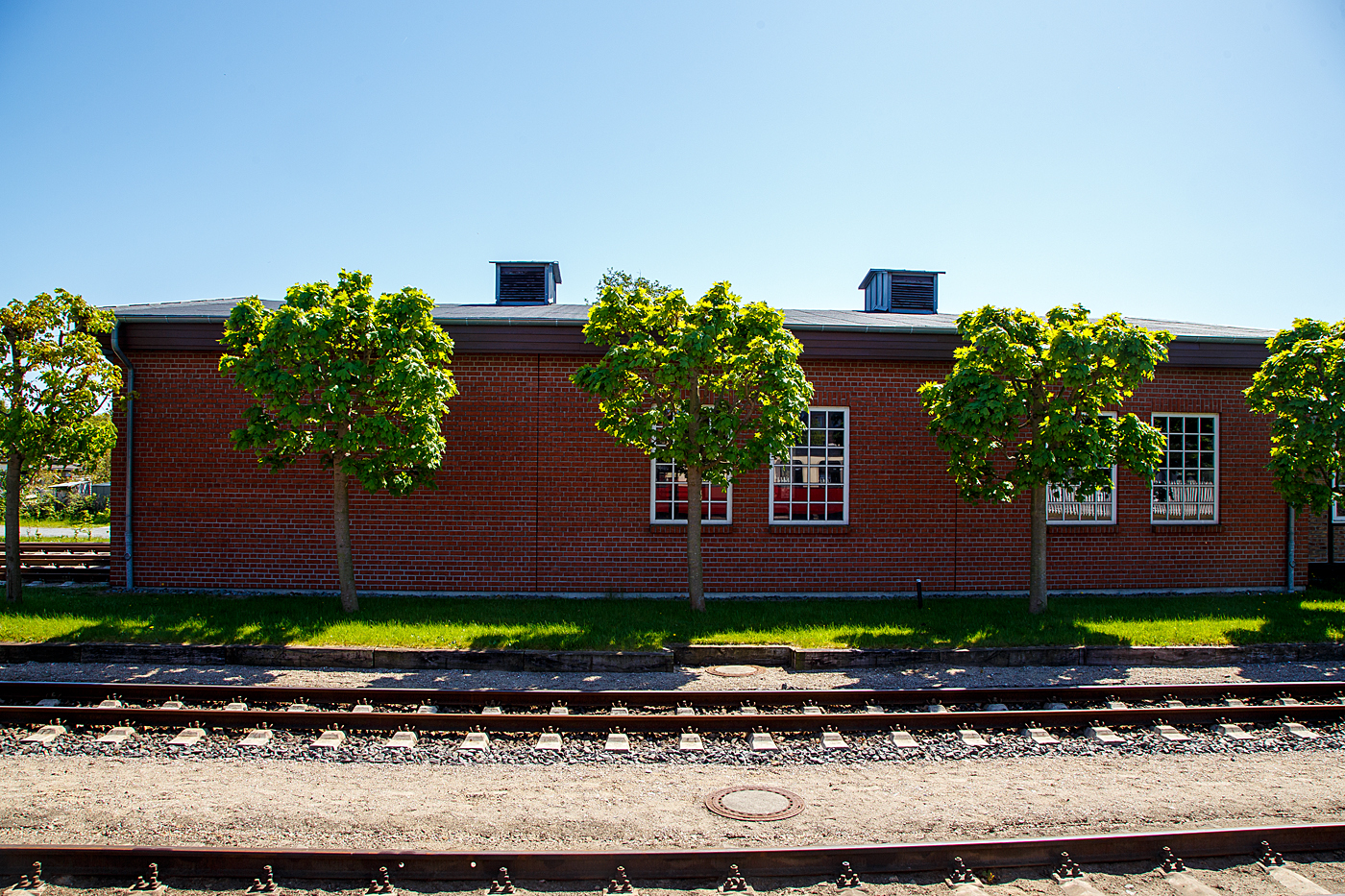 Der Seitenansicht vom Lokschuppen der Mecklenburgischen Bäderbahn Molli GmbH (MBB) im Ostseebad Kühlungsborn West, hier am 15 Mai 2022. In den Fenstern spiegelt sich ein Wagen.