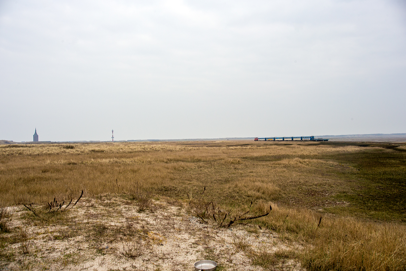 Der Verlust von mehr als zwei Milliarden Euro reicht der DB AG wohl nicht ganz aus. Wir hätten auch den Fahrpreis für die Einzelfahrt von 3,30 Euro/Person wie laut Preisliste auch gezahlt, aber trotzdem kann man nicht mit dem nun leeren Personenzug vom Westanleger zum Bahnhof Wangerooge fahren. Gut am Westanleger gibt es keinen Automaten und die Züge der Wangerooger Inselbahn  bzw. der SIW - Schifffahrt und Inselbahn Wangerooge (gehört zur DB Fernverkehr AG) haben keinen Schaffner (nur einen Rangierbegleiter), aber den Fahrpreis könnte man ja auch bei der Ankunft entrichten. 

So fährt nun die DB 399 108-0 (98 80 3399 108-0 D-DB) der Wangerooger Inselbahn am 12 März 2024, mit dem Personenzug und zwei Flachwagen (für Gepäckcontainern) nun ganz leer, Westanleger Wangerooge zum Bahnhof Wangerooge, durch die Salzwiesen, zurück. Mit unseren 6,60 Euro wäre wohl schon der Diesel für die Leerfahrt bezahlt und wir waren nicht die Einzigen die mit gefahren wären.

Links in Bild der Westturm der Jugendherberge (DJH), rechts davon der aktive 67,2 m hohe Neue Leuchtturm Wangerooge.
