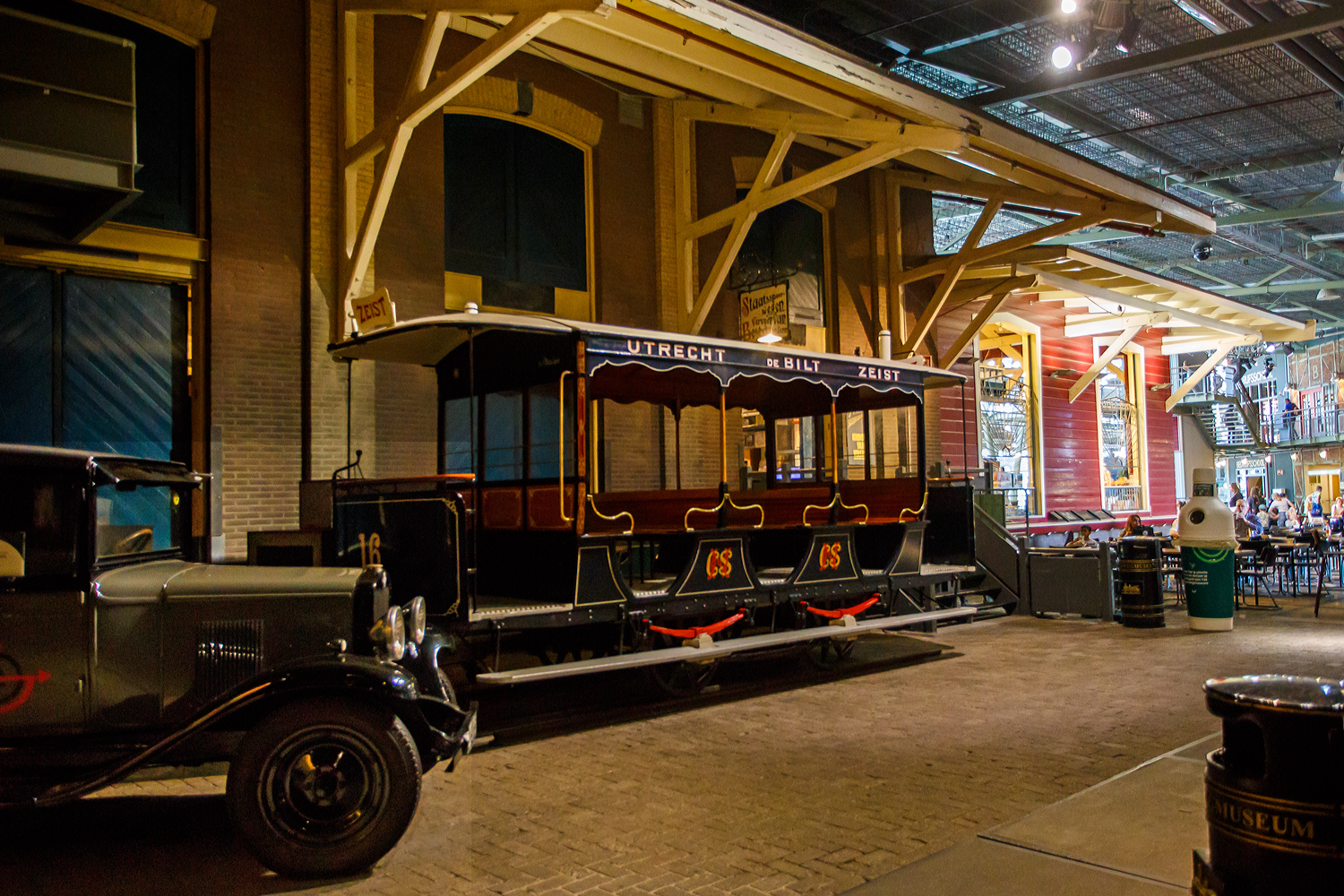 Der zweiachsige Pferdebahnwagen STM 16 der Pferdebahn Utrecht - De Bilt – Zeist der ehemaligen STM - Stichtsche Tramway-Maatschappij, ab 1901 NBM - Nederlandsche Buurtspoorweg-Maatschappij, am 29 April 2025 im Het Spoorwegmuseum (bis 2005 NSM - Nederlands Spoorwegmuseum / Niederländischen Eisenbahnmuseum) in Utrecht - Maliebaan im ehemaligen Bahnhof Maliebaan. Ein Eisenbahnmuseum das wahrhaft zum Verweilen einlädt, leider fehlte uns dieses Mal die Zeit dafür.

Der Wagen wurde 1891 von Beijnes, offiziell Koninklijke Fabriek van Rijtuigen en Spoorwagens J.J. Beijnes (Königliche Fabrik für Kutschen und Eisenbahnwagen J.J. Beijnes) in Haarlem gebaut und an die damalige STM - Stichtsche Tramway-Maatschappij geliefert.

Ende des 19. und Anfang des 20. Jahrhunderts verkehrten in der Stadt und Provinz Utrecht bereits Straßenbahnen der ersten Generation. So u.a. von 1879 bis 1949 eine Überlandstraßenbahn Utrecht - De Bilt – Zeist, betrieben zunächst durch die STM Stichtsche Tramway-Maatschappij, übernommen im Jahr 1901 durch die Nederlandsche Buurtspoorweg-Maatschappij. Diese war bis 1909 eine Pferdebahn beförderte Fahrgäste vom Utrechter Hauptbahnhof durch die Voorstraat und Biltstraat in das schicke Städtchen Zeist. Ab 1909 wurde sie eine elektrische Überlandstraßenbahn. So wurde dieser Anhänger ab 1909 meist im Sommer von der elektrischen Straßenbahn gezogen. Die Überlandstraßenbahn war teilweise auch für die Schließung des Bahnhofs Maliebaan, dem heutigen Eisenbahnmuseum, verantwortlich. Viele Fahrgäste aus Richtung Hilversum wählten zum Ein- und Aussteigen die Haltestelle Biltstraat. Von dort aus bot diese Bahn eine bessere Verbindung ins Stadtzentrum von Utrecht, sodass es keinen Grund mehr gab, weiter zum Bahnhof Maliebaan zu fahren. 

Die STM 16 ist das älteste noch erhaltene Beispiel einer wichtigen Phase in der Geschichte des niederländischen Schienenverkehrs, der Überland-Pferdebahnlinien. Der zweiachsige Wagen/Anhänger war bis 1946 in Betrieb.

Quellen: Het Spoorwegmuseum und nmld.nl
Stand/Überarbeitung: September 2025
