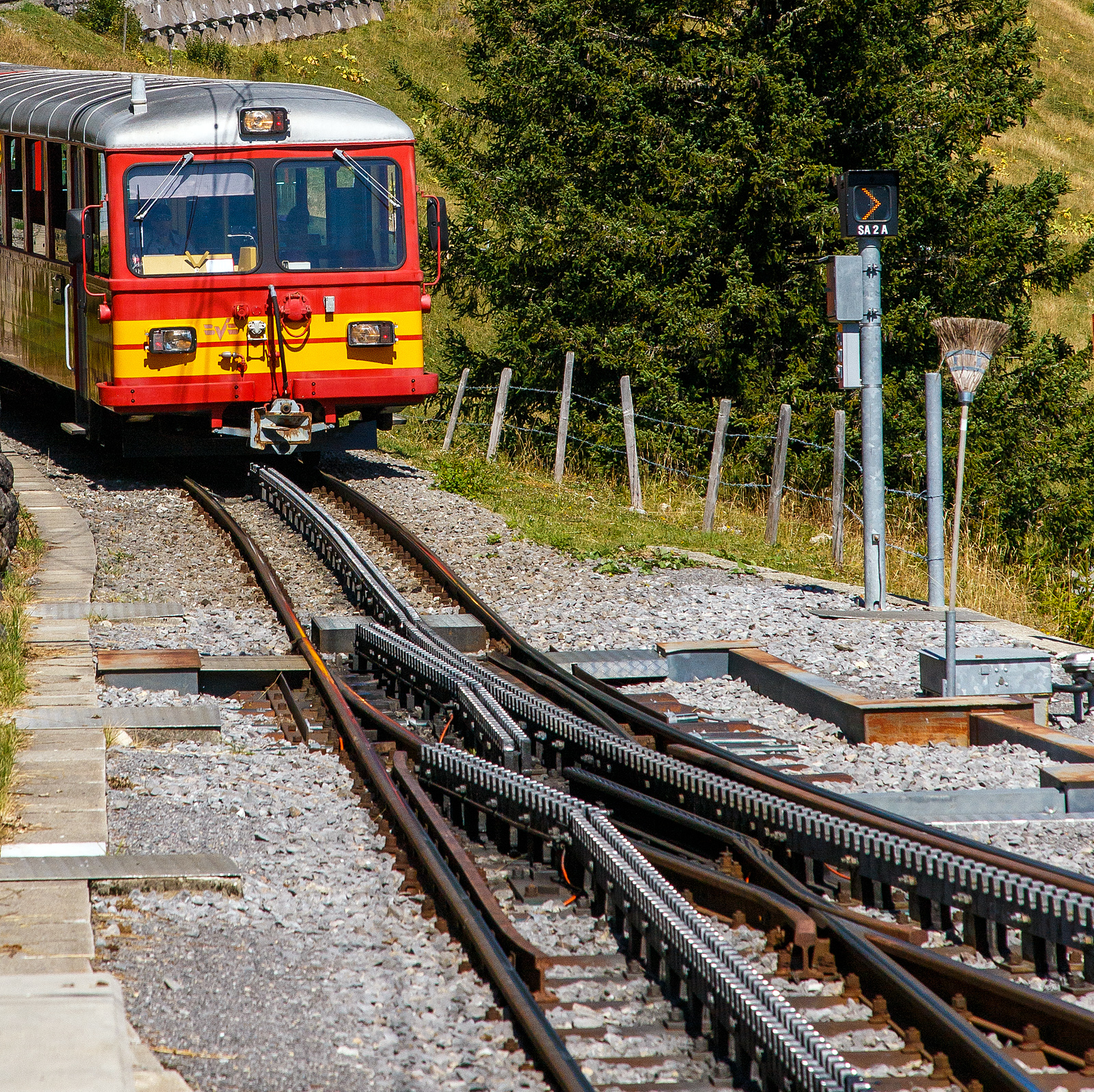 Deteilbild einer Weiche der zweilamelligen hochliegenden Zahnstangen vom System Abt, hier der tpc BVG - Chemin de fer Bex–Villars–Bretaye, hier am 10 September 2023 beim Haltepunkt Bouquetins auf 1.758 m ü. M, der Strecke 128 (Villars-sur-Ollon–Col-de-Bretaye).Geführt von dem Steuerwagen tpc BVB Bt 54 kommt der tpc BVB Pendelzug (Steuerwagen BVB Bt 54, Personenwagen tpc BVB B 51 und die BVB HGe 4/4 32 „Villars“) vom Bergbahnhof Col-de-Bretaye (1.808 m ü. M.) hinab.

Die tpc Strecke BVB, deutsch Bex–Villars–Bretaye-Bahn, ist eine 17 km lange Schmalspurbahn in der Spurweite 1.000 mm mit gemischtem Adhäsions- und Zahnradbetrieb. Das 4,65 km Teilstück (BAV-Strecke 128) von Villars-sur-Ollon (1.252 m ü. M.) auf den Col-de-Bretaye (1.808 m ü. M) ist vollständig mit einer Zahnstange System Abt versehen und hat eine maximale Steigung von 170 Promille.