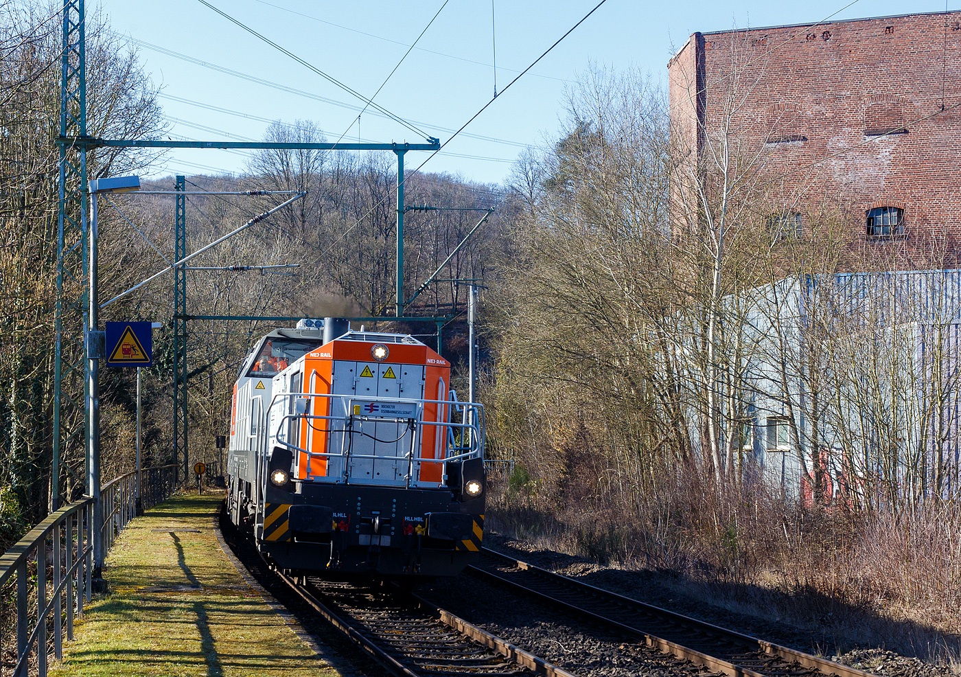 Die an die BEG - Bocholter Eisenbahngesellschaft mbH vermietete 4185 132-2 „Christa“ (92 80 4185 132-2 D-NXRL), eine Vossloh DE 18 der Nexrail AssetCo Sàrl (Luxembourg) fährt am 17 Februar 2025, mit dem Kirow KRC 1200 Kranzug (Multi Tasker, 150-Mp-Kran) der MGW Gleis- und Weichenbau-GmbH & Co.KG (Berlin), durch Scheuerfeld/Sieg in Richtung Siegen. Hinter der Lok sind der Schutzwagen D-MGWB 37 80 3999 232-4, der KRC 1200 Kranwagen D-MGWB 99 80 9519 003-4 und der Gegenlastwagen D-MGWB 99 80 9310 031-6.

Die dieselelektrische Lokomotive wurde 2024 von der Vossloh Rolling Stock GmbH in Kiel unter der Fabriknummer 5502607 gebaut. Im Juni 2024 wurde sie an die BEG vermietet.

Die DE 18 ist eine dieselelektrische Lokomotive für den Rangier- und Streckendienst von der Vossloh Rolling Stock GmbH. Der dieselelektrische Antrieb der vierachsigen Lok bietet hohe Wirkungsgrade und eine redundante Architektur mit hoher Ausfallsicherheit. Auch zukünftige Innovationen wie die Hybrid- und Speichertechnik sind mit den dieselelektrischen Modellen möglich. Dank ihrer universalen Einsatzmöglichkeiten hat sich die DE 18 bei vielen Betreibern etabliert. 

TECHNISCH DATEN:
Spurweite: 1.435 mm (Normalspur)
Achsanordnung:  Bo’Bo’
Länge über Puffer: 17.000 mm  
Größte Höhe: 4.310 mm  
Größte Breite: 3.080 mm
Achsabstand im Drehgestell: 2.400 mm
Raddurchmesser:  1.000 mm (neu) / 920 mm (abgenutzt)
Dieselmotor: wassergekühlter V12-Zylinder-Dieselmotor mit Abgasturbolader und Ladeluftkühlung vom Typ MTU 12V 4000 R43(L) 
Dieselmotorleistung: 1.800 kW (1.600 kW am Rad)
Dieselmotordrehzahl: 1.800 U/min
Abgasvorschriften: Stufe V gemäß EU-Verordnung 2016/1628
Höchstgeschwindigkeit:120 km/h
Anfahrzugkraft: 91 kN
Dienstgewicht: 90 t
Kraftstoffvorrat: 3.700 l
Kraftübertragung: radsatzselektiv AC/AC
Stromrichter: IGBT-Wechselrichter
Elektrodynamische Bremsleistung: max. 1.450 kW 	
Kleinster befahrbarer Bogenradius: 75 m