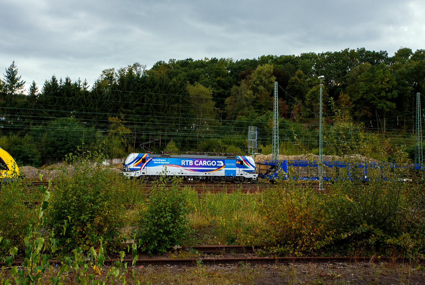 Die an die RTB Cargo vermietete Siemens Vectron MS - 6193 174 „Gemeinsam durch Europa“ (91 80 6193 174-0 D-Rpool) der Railpool GmbH (München) fährt am 28 September 2025 mit einem leeren Autotransportzug durch den Betzdorf/Sieg in Richtung Siegen. 

Die Multisystemlokomotive Siemens Vectron MS wurde 2024 von SIEMENS Mobilitiy in München-Allach unter der Fabriknummer 23474 gebaut und im September 2024 an die Railpool ausgeliefert. Hier in der ausgeführten Variante MS A54 ist sie eine „echte“ Multisystemlokomotive und kann in halb Europa fahren. Sie hat die Zulassungen und Länderpakete für Deutschland, Österreich, Belgien, die Niederlande, Tschechien, die Slowakei, Ungarn, Rumänien und Polen. Für Serbien (SRB), Bulgarien (BG) und Kroatien (HR) sind auch Zulassungen vorgesehen, aber ist z.Z. noch durchgestrichen.

So besitzt die Variante MS A54 folgende Zugsicherungssysteme: ETCS BaseLine 3, sowie für Deutschland (PZB90 / LZB80 (CIR-ELKE I)), für Österreich (ETCS Level 1 mit Euroloop, ETCS Level 2, PZB90 / LZB80), für Belgien (ETCS L1, ETCS L2, TBL1+), für die Niederlande (ETCS Level 1, ETCS Level 2, ATB-EGvV), für Tschechien und die Slowakei (LS (Mirel)), für Ungarn (ETCS Level 1, EVM (Mirel)), für Polen (SHP) und für Rumänien, Serbien, Bulgarien und Kroatien (PZB90).
