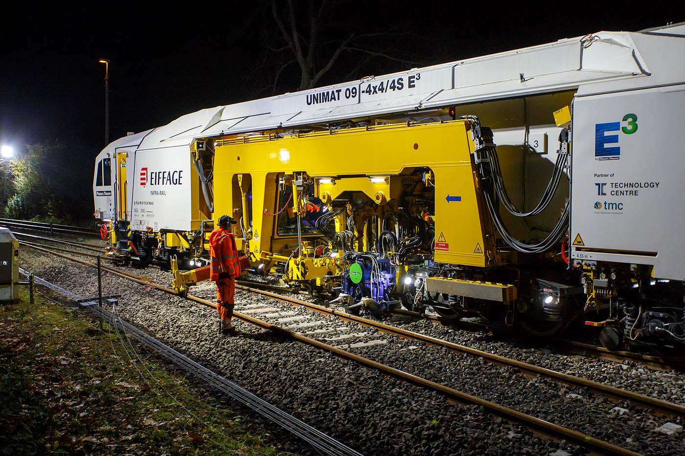 Die Baustelle Bahnhof Herdorf am Abend des 26 Oktober 2025, nun ab 20:40 Uhr wird die neue Weiche 3, beim Bahnhof/Stellwerk Herdorf Fahrdienstleiter (Hf), gestopft. Hier kam die recht neue Plasser & Theurer UNIMAT 09-4x4/4S E� (A-PLA 99 81 9124 004-8), eine Universal-Weichenstopfmaschine mit Hybrid-Antriebstechnik, der Firma Eiffage Infra-Rail GmbH (Herne) zum Einsatz. Ob die Maschine nur von Eiffage Infra-Rail gemietet oder nun gekaut wurde ist mir nicht klar, aber eingestellt ist sie in �sterreich �ber Franz Plasser Vermietung von Bahnbaumaschinen GmbH.

Detailbild vom Stopfvorgang, hier kann am auch gut erkennen was u.a. eine Weichenstopfmaschine ausmacht, die Stopfpickel sind u.a. einzeln wegschwenkbar. 