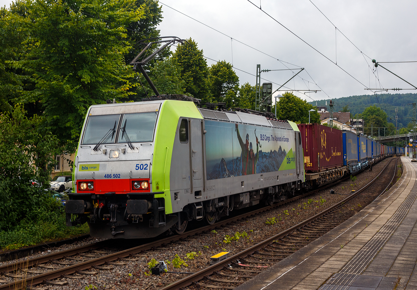 Die BLS Cargo 502, Re 486 502-8/E 486 502 SF  The Alpinists in Europa  (91 85 4486 502-8CH-BLSC) f�hrt am 07 Juli 2025 mit einem HUPAC KLV-Zug durch Kirchen (Sieg) in Richtung K�ln.

Nochmals einen lieben Gru� an den netten Lokf�hrer zur�ck.

Die TRAXX F140 MS wurde 2008 von Bombardier in Kassel unter der Fabriknummer 34401 gebaut und an die BLS Cargo AG (Bern) geliefert. Die Loks sind nur f�r die Schweiz, Deutschland, �sterreich und Italien zugelassen.

Der Erfolg im G�terverkehr veranlasste die BLS zehn weitere TRAXX zu bestellen im Gegensatz zur ersten Serie TRAXX F140 AC1 mit der Bezeichnung Re 485 001 bis 485 020, die nur unter Wechselstrom fahren k�nnen, k�nnen die TRAXX F140 MS Re 486 501 bis 486 510 auch unter 3.000 Volt Gleichstrom eingesetzt werden. Bombardier hatte seit der ersten Lieferung Verbesserungen vorgenommen. Dabei wurde der Lokomotivkasten optimiert und die Traktionsausr�stung mit moderneren Komponenten versehen. Eine Nachbeschaffung w�re noch m�glich gewesen, h�tte aber dazu gef�hrt, dass die Lokomotiven nicht auf dem neuesten Stand waren und nicht unter der Gleichstromfahrleitung eingesetzt werden konnten. Die eingebauten Zugbeeinflussungssysteme erlauben den Einsatz in Deutschland, �sterreich, der Schweiz und Italien (DACHI). Anf�nglich waren die Lokomotiven in der Schweiz nur f�r den Einsatz auf Strecken mit konventioneller Zugbeinflussung und nicht auf ETCS Level 2 Strecken zugelassen. Die Re 486 k�nnen unter sich und mit den Re 485 und Lokomotiven der Baureihe 185/186 in Vielfachsteuerung eingesetzt werden. Mittlerweile nach Umbauten durch die BLS, k�nnen die Loks nun auch mit Re 465, sowie mit Siemens Vectron der BR 193 bzw. Re 475 in Mehrfachtraktion gefahren werden.

TECHNISCHE DATEN:
Spurweite: 1.435 mm (Normalspur)
Achsformel: Bo’Bo’
L�nge �ber Puffer: 18.900 mm
H�he: 4.385 mm
Breite: 2.978 mm
Drehzapfenabstand: 10.400 mm
Achsabstand im Drehgestell: 2.600 mm
Dienstmasse: 85 t
H�chstgeschwindigkeit:  140 km/h
Dauerleistung: 5.600 kW
Dauerzugkraft: 300 kN
Treibraddurchmesser: 1.250 mm
Stromsysteme: 15 kV 16,7 Hz, 25 kV 50 Hz Wechselstrom sowie 3 kV und 1,5 kV Gleichstrom
Antrieb: Tatzlager