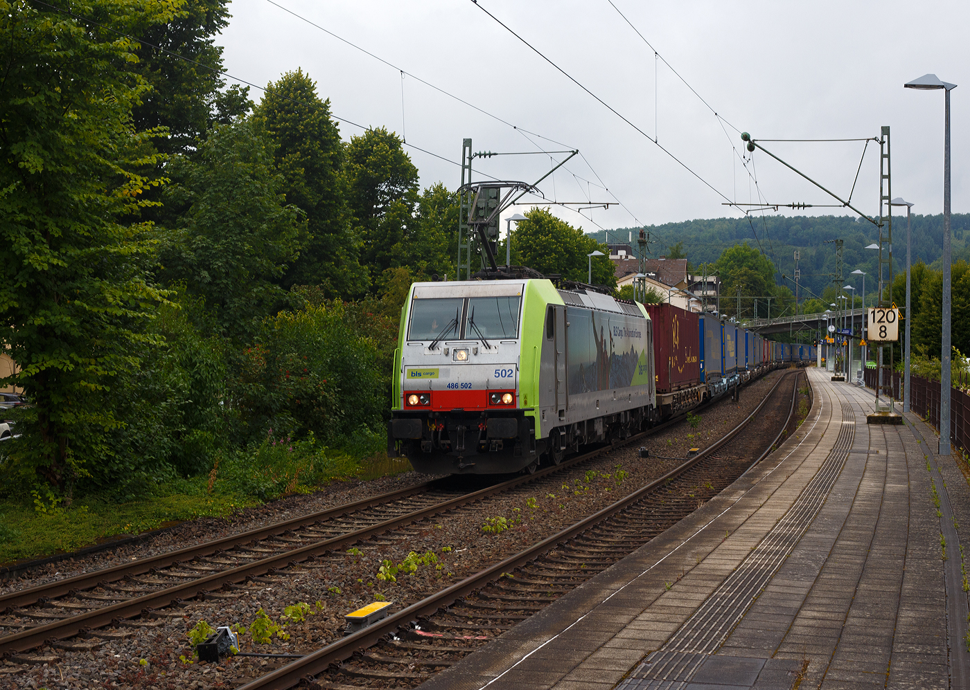 Die BLS Cargo 502, Re 486 502-8/E 486 502 SF  The Alpinists in Europa  (91 85 4486 502-8CH-BLSC) f�hrt am 07 Juli 2025 mit einem HUPAC KLV-Zug durch Kirchen (Sieg) in Richtung K�ln.

Nochmals einen lieben Gru� an den netten Lokf�hrer zur�ck.

Die TRAXX F140 MS wurde 2008 von Bombardier in Kassel unter der Fabriknummer 34401 gebaut und an die BLS Cargo AG (Bern) geliefert. Die Loks sind nur f�r die Schweiz, Deutschland, �sterreich und Italien zugelassen.

Der Erfolg im G�terverkehr veranlasste die BLS zehn weitere TRAXX zu bestellen im Gegensatz zur ersten Serie TRAXX F140 AC1 mit der Bezeichnung Re 485 001 bis 485 020, die nur unter Wechselstrom fahren k�nnen, k�nnen die TRAXX F140 MS Re 486 501 bis 486 510 auch unter 3.000 Volt Gleichstrom eingesetzt werden. Bombardier hatte seit der ersten Lieferung Verbesserungen vorgenommen. Dabei wurde der Lokomotivkasten optimiert und die Traktionsausr�stung mit moderneren Komponenten versehen. Eine Nachbeschaffung w�re noch m�glich gewesen, h�tte aber dazu gef�hrt, dass die Lokomotiven nicht auf dem neuesten Stand waren und nicht unter der Gleichstromfahrleitung eingesetzt werden konnten. Die eingebauten Zugbeeinflussungssysteme erlauben den Einsatz in Deutschland, �sterreich, der Schweiz und Italien (DACHI). Anf�nglich waren die Lokomotiven in der Schweiz nur f�r den Einsatz auf Strecken mit konventioneller Zugbeinflussung und nicht auf ETCS Level 2 Strecken zugelassen. Die Re 486 k�nnen unter sich und mit den Re 485 und Lokomotiven der Baureihe 185/186 in Vielfachsteuerung eingesetzt werden. Mittlerweile nach Umbauten durch die BLS, k�nnen die Loks nun auch mit Re 465, sowie mit Siemens Vectron der BR 193 bzw. Re 475 in Mehrfachtraktion gefahren werden.

TECHNISCHE DATEN:
Spurweite: 1.435 mm (Normalspur)
Achsformel: Bo’Bo’
L�nge �ber Puffer: 18.900 mm
H�he: 4.385 mm
Breite: 2.978 mm
Drehzapfenabstand: 10.400 mm
Achsabstand im Drehgestell: 2.600 mm
Dienstmasse: 85 t
H�chstgeschwindigkeit:  140 km/h
Dauerleistung: 5.600 kW
Dauerzugkraft: 300 kN
Treibraddurchmesser: 1.250 mm
Stromsysteme: 15 kV 16,7 Hz, 25 kV 50 Hz Wechselstrom sowie 3 kV und 1,5 kV Gleichstrom
Antrieb: Tatzlager