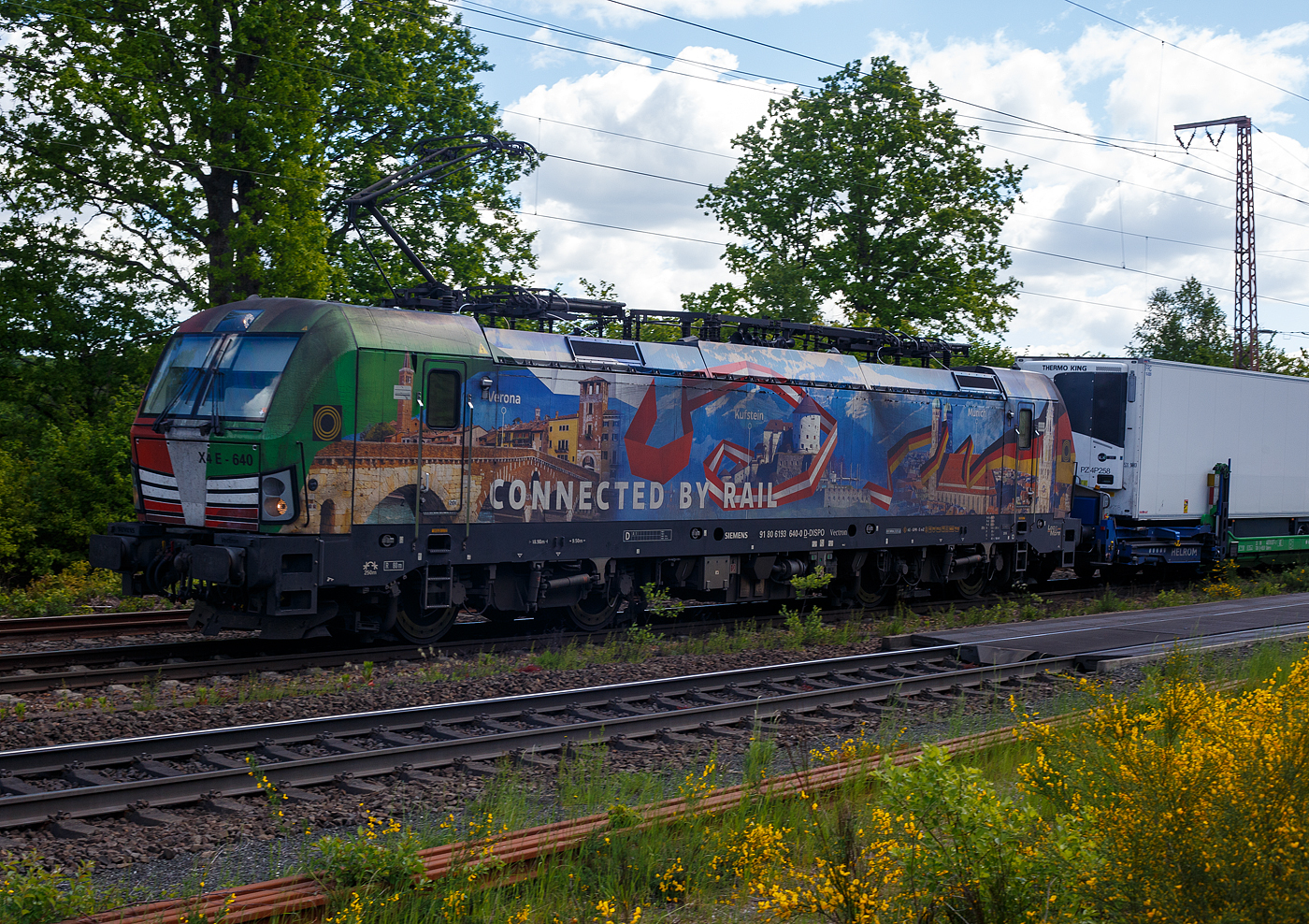 Die bunte und schöne Siemens Vectron MS X 4 E – 640 / 193 640-0 “Connected by Rail” (91 80 6193 640-0 D-DISPO) der Beacon Rail Capital Europe GmbH, München (BRCE / DISPO) fährt am 16 Mai 2025 mit dem HELROM Trailer Zug Wien – Düsseldorf, einem besonderen KV-Zug, durch Ruderdorf (Kr. Siegen), via Siegen, in Richtung Köln. Leider war die Lok hier nicht ganz sauber, zudem war eine Wolke vor der Sonne.

Die Siemens Vectron MS - 6.4 MW wurde 2016 von Siemens in München-Allach unter der Fabriknummer 22164 gebaut. Sie ist in der Variante A09 ausgeführt und hat so die Zulassungen für Deutschland, Österreich und Italien (D / A / I), daher trägt sie auch die Werbung München, Kufstein, Verona (Connected by Rail). Sie hat eine Höchstgeschwindigkeit von 160 km/h.

Die Lok wurde an die MRCE - Mitsui Rail Capital Europe GmbH in München ausgeliefert, seit September 2023 hat die Beacon Rail Metro Finance B.V. die Mitsui Rail Capital Europe B.V. (Amsterdam) und somit auch die Mitsui Rail Capital Europe GmbH im München übernommen, so firmiert sie nun als Beacon Rail Capital Europe GmbH, München (BRCE / DISPO).
