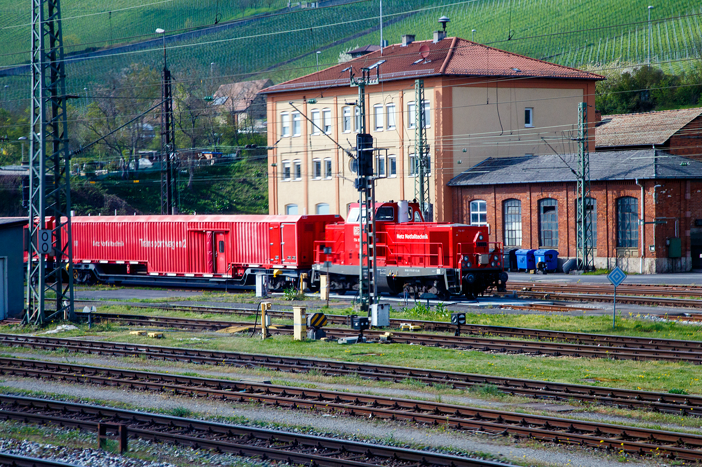 Die DB Rettungszug Lok (Neue Umbaulok für TRZ/Tunnelrettungszug) 714 107
(UIC 99 80 9170 007-5 D-DB) der DB Netz (Notfalltechnik) steht am 21 April 2023 mit dem Würzburger Rettungszug beim Hbf Würzburg. Die Aufnahme entstand aus einem fahrenden Zug durch die Scheibe. 

Die Ursprungslok (V 100.20) wurde 1965 von der Maschinenbau Kiel (MaK) unter der Fabriknummer 1000318 gebaut und als V 100 2271 an die Deutsche Bundesbahn geliefert, weiterer Lebenslauf und Bezeichnungen siend:
01.01.1968 - Umzeichnung in DB 212 271-1
01.01.1989 - Umzeichnung in DB 214 271-9 (Rettungszuglok)
31.10.1994 - Umzeichnung in DB 714 271-4
01.08.1996 - Umzeichnung in DB 714 011-4
2016 - Modernisierung  Tunnelhilfszuglok  im Werk Bremen-Sebaldsbrück der DB Fahrzeuginstandhaltungs GmbH und Umzeichnung in DB 714 107 (NVR: 99 80 9170 007-5 D-DB)

Die Loks (TuHi/Rtz) der neuen BR 714.1 (UCI Nr. 99 80 9 170....D-DB) sind neu grundlegend umgebaute Loks der BR 714.0, ex 714.2, ex BR 214, diese wiederum waren umgebaute Loks der BR 212 bzw. ex DB V 100.20. Die Ursprungslok ist optisch äußerlich kaum noch auszumachen, Drehgestelle und Rahmen sind wohl die alten. Ob Motor und Getriebe noch die alten sind kann ich hier nicht sagen. Modernisierung zur  Tunnelhilfszuglok  (BR 714.1 / UCI Nr. 99 80 9 170....D-DB ) wurde im Werk Bremen-Sebaldsbrück der DB Fahrzeuginstandhaltungs GmbH durchgeführt. Es ist u.a. das Kompetenzzentrum für die Instandhaltung von Großdieselmotoren. Dort wurden 14 Loks modernisiert, sie erhielten hierbei neue Führerhäuser mit Türen zum Seitenumlauf, eine neue Steuerung für die Elektrik, Rußpartikelfilter sowie neue Kühlanlagen mit Lüftern. Die modernisierten Loks werden nun als Baureihe 714.1 geführt, werden im Fahrzeugeinstellungsregister (National Vehicle Register, kurz: NVR) als 99 80 9 170 0xx-x D-DB geführt.

TECHNISCHE DATEN:
Spurweite: 1.435 mm (Normalspur)
Achsfolge:  B´B´
Länge über Puffer: 12.300 mm
Drehzapfenabstand: 6.000 mm
Drehgestellachsstand: 2.200 mm
größte Breite: 3.115 mm
kleinster befahrbarer Gleisbogen: 100 m
Dienstgewicht: 62 t
Höchstgeschwindigkeit: 100 km/h
Kraftstoffvorrat: 2.400 l

