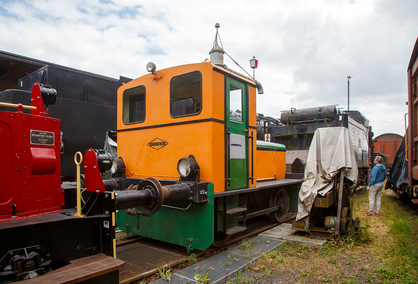 Die DEUTZ 56792 eine Deutz  Typ  A4L 514 R  eine Leihgabe an die Westerwälder Eisenbahnfreunde 44 508 e. V. steht am 02.07.2023 beim Lokschuppen beim Erlebnisbahnhof Westerwald in Westerburg, hier war Lokschuppen-/Sommerfest.

Die Lok wurde 1957 bei KHD unter der Fabriknummer 56792 gebaut und am 27.01.1958 an die Stadtwerke Gießen ausgeliefert.

Die Diesellokomotive der Bauart A4L 514 R wurde von der Klöckner-Humboldt-Deutz AG in Köln entwickelt und gebaut. Die A4L 514 R war der Nachfolger der erfolgreichen Vorkriegstype OMZ 122 R. Die für den leichten Rangierdienst vorgesehene Lokomotive verfügt über einen 55 PS starken luftgekühlten 4-Takt Dieselmotor, der die Maschine bei einem Dienstgewicht von 14 Tonnen auf die größte zulässige Geschwindigkeit von 15 Km/h beschleunigt. Die Lokomotive wurde in großer Stückzahl in unterschiedlichen Spurweiten gebaut und fand weltweite Verbreitung. Einfacher Aufbau und Robustheit bescherten den Lokomotiven oftmals einen sehr langen Einsatzzeitraum. Auch heute sind diese Loks zum Teil noch im Einsatz anzutreffen. Als KS 55 B fand die Konstruktion unverändert Eingang in das Typenprogramm 1959.

Die Leitungsübertragung erfolgte vom luftgekühlten Vierzylindermotor über ein mechanisches Vier-Gang-Getriebe auf die Hinterachse, über Stangen wurde die Kraft auch auf die vordere Achse übertragen.
  
TECHNISCHE DATEN:
Baujahre: 1950 - 1960
gebaute Stückzahl: 175
Spurweite: 1.435 mm (Normalspur)
Achsfolge : B (zwei Achsen)
Länge über Puffer:  5.730 mm 
Achsabstand: 2.500 mm
größte Breite 2.538 mm
größte Höhe über Schienenoberkante 3.017 mm
Treibraddurchmesser: 850 mm (neu)
Dienstgewicht:  14 t
zulässige Höchstgeschwindigkeit: 14,5 km/h
Anfahrzugkraft:  3.460 kg / 34,6 kN
Dieselmotor: luftgekühlter 4-Takt 4-Zylinder Reihenmotor vom Typ Deutz A4L 514
Motorhubraum: 5,322 Liter (Bohrung 110 mm x 140 mm Hub)
Leistung  55 PS bei 1500 U/min 
Motorgewicht: ca. 500 kg (Abm. 1.080 x 740 x 1.030 mm)
Getriebe: mech. Deutz 4 Gang-Getriebe
Bremse: mech. Fussbremse
