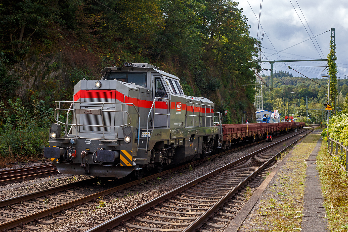 Die dieselhydraulische Vossloh G 12 – 4120 001-7 „Karl August“ (92 80 4120 001-7 D-KAF) der KAF Falkenhahn Bau AG (Kreuztal) fährt am 11 September 2024 mit Zug, bestehend aus leeren 4-achsiger Drehgestell-Flachwagen mit Seitenborden, Stirnwänden und Stahlfußboden, der Gattung Res-x 679.1 der DB Cargo AG, durch Scheuerfeld (Sieg) in Richtung Betzdorf (Sieg).

Übrigens, die Lok trägt den Namen des Firmengründers Karl August Falkenhahn, der die Baufirma 1919 in Kreuztal gründete. Die G12 wurde 2010 von Vossloh in Kiel unter der Fabriknummer 5001919, als Prototyp, gebaut und bereits auf der InnoTrans 2010 präsentiert, 2014 konnte ich sie selbst auf der InnoTrans 2014 als SLG Spitzke G 12 - SP - 012 (92 80 4120 001-7 D-VL) sehen und ablichten. Im Jahr 2017 wurde die Lok an die KAF Falkenhahn Bau AG (Kreuztal) verkauft. Aus Fachkreisen kann man hören dass es wohl nicht so ein guter Wurf war und so bleibt diese G 12 wohl ein Einzelstück. Lediglich von der diesel-elektrischen Variante (DE 12) wurden bisher 5 Stück gebaut. Die leistungsstärkere Serie G18 / DE 18 ist erheblich erfolgreicher.

Die G 12 wie auch die G 18 sind neue dieselhydraulische Lokomotiven der fünften Generation für den schweren Rangier- und Streckendienst von Vossloh Locomotives. Die G 12 mit 1.200 kW sowie die G 18 mit 1.800 kW. Angetrieben werden die Vierachser von den optimierten Turbo-Flex-Getrieben von Voith. Ein neues Drei-Wandler-Getriebe verbessert den Wirkungsgrad und ist mit einem leistungsfähigen Retarder zum verschleißfreien Bremsen ausgerüstet. Das Gesamtgewicht der Loks kann flexibel zwischen 80 und 90 t ausgelegt werden.

TECHNISCHE DATEN:
Spurweite: 1.435 mm (Normalspur)
Achsfolge: B‘B‘
Höchstgeschwindigkeit: 100 km/h
Dieselmotorleistung: max. 1.200 kW
Dieselmotor: MTU 8V 4000 R43 (L)
Dieselmotordrehzahl 1.800 min-1
Abgasvorschriften: EU/2004/26 Stufe IIIA/prepared for stage IIIB
Anfahrzugkraft: 259 kN
Dienstgewicht: 80 t
Raddurchmesser: 1.000 mm (neu) / 920 mm (abgenutzt)
Länge über Puffer : 17.000 mm
Größte Höhe: 4.310 mm
Größte Breite: 3.080 mm
Drehzapfenabstand: 8.100 mm
Achsabstand im Drehgestell: 2.400 mm
Strömungsgetriebe: Voith L 4r4 zseU2
Hydrodynamische Bremsleistung: max. 1.000 kW
Kleinster befahrbarer Bogenradius: 55 m
