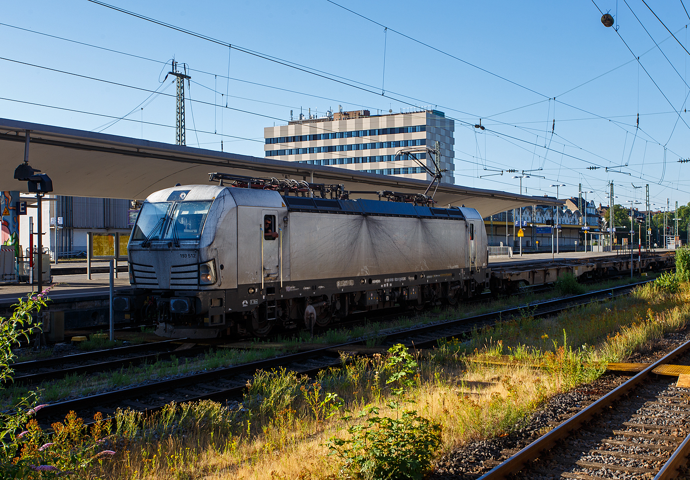 Die eigentlich „weiße“ SIEMENS Vectron MS 193 512-1 (91 80 6193 512-1 D-ELOC) der ELL - European Locomotive Leasing (Wien) hat am 01 Juli 2025 mit einem KLV-Zug in Richtung Köln fahrend im Hauptbahnhof Koblenz Hp 0. 

Nochmals einen lieben Gruß an den sehr netten Lokführer zurück. Leider war eine richtige Unterhaltung über die Gleise hinweg, wegen dem durchfahrendem Gegenzug, nicht richtig möglich und nach einem eingefahren FLIRT gar nicht mehr.

Die SIEMENS Vectron MS - 6.4 MW wurde 2023 von Siemens in München-Allach unter der Fabriknummer 23530 gebaut. Sie ist in der Variante A10-7i ausgeführt und hat so die Zulassungen für Deutschland, Österreich, Polen, Tschechien, Slowakei, Ungarn, Niederlande, Rumänien und Bulgarien (D / A / PL / CZ / SK / H / NL / RO und BG).

So besitzt die Variante MS A10-7i folgende Zugsicherungssysteme: ETCS BaseLine 3, sowie für Deutschland (PZB90 / LZB80 (CIR-ELKE I)), für Österreich (ETCS Level 1 mit Euroloop, ETCS Level 2, PZB90 / LZB80), für Polen (SHP), für Tschechien und die Slowakei (LS (Mirel)), für Ungarn (ETCS Level 1, EVM (Mirel)) für die Niederlande (ETCS Level 1, ETCS Level 2, ATB-EGvV) und für Rumänien und Bulgarien (PZB90).
