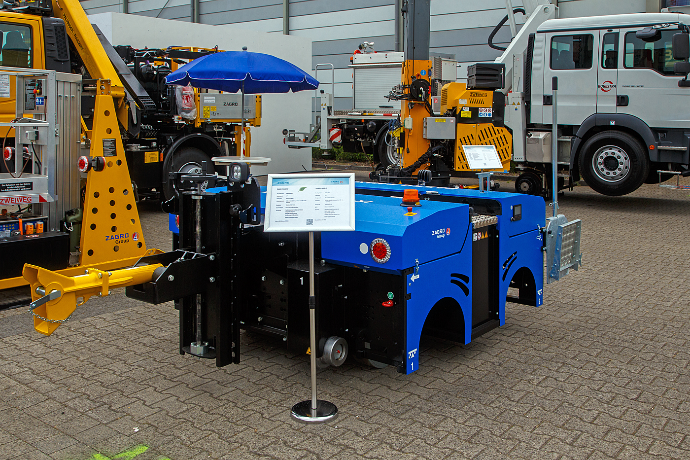 Die Firma ZAGRO Bahn- und Baumaschinen GmbH aus Bad Rappenau-Grombach präsentierte auf der 28. Internationale Ausstellung Fahrwegtechnik 2022 (iaf) in Münster, hier am 31 Mai 2022, einen Meterspur-Rangierer ZAGRO E-MAXI M. Übrigens zur ZAGRO Group gehören auch die Firmen ZWEIWEG International GmbH in Leichlingen und GMEINDER LOKOMOTIVEN GmbH in Mosbach (Baden).

Im Jahr 2020 nach 12 Jahren E-MAXI Produktion gab es eine neue Generation der emissionsfreien Rangierer der ZAGRO E-MAXI Serie. Der wendig, 4,5 Tonnen schwere Elektrorangierer ZAGRO E-MAXI M ist ideal für Rangierarbeiten in Depots und/oder außerhalb des Betriebsgeländes. Durch die patentierte Allradlenkung ist der Einsatz auf engstem Raum möglich. Das Wenden auf der Stelle funktioniert ohne erhöhten Reifenverschleiß. Verschiedene Kuppelsysteme, auch kundenspezifische Lösungen sind realisierbar. Die Steuerung des Rangierfahrzeugs erfolgt über eine Funkfernbedienung im Ein-Mann-Betrieb. Standardmäßig gibt es zwei Einstellungen der Fahrgeschwindigkeit: von 0 bis 3 km/h und von 0 bis 6 km/h. Dabei kann das Fahrzeug für unterschiedliche Schienenspurweiten von 1.000 mm bis 1.676 mm konzipiert werden. Das ausgestellte Fahrzeug ist für die Spurweite 1.000 mm (Meterspur).

Auf engstem Raum ist ein schneller Gleiswechsel möglich:
Die Spurführung kann per Knopfdruck hydraulisch angehoben und abgesenkt werden. Die vier Laufräder werden einfach per Lenkrad oder Fernsteuerung um max. 130° geschwenkt. Der Abrieb der Laufräder, die in Gummi- oder Vulkollanausführung erhältlich sind, kann dadurch selbst beim Wenden
auf der Stelle auf ein Minimum reduziert werden.

TECHNISCHE DATEN:
Spurweite: 1.000 mm (möglich 1.000 mm bis 1.676 mm)
Abmessungen (L x B x H): 2.110 mm x 2.170 mm x 1.190 mm
Antriebsart: elektrisch durch Batterie
Eigengewicht: 4,7 t
Höchstgeschwindigkeit (Schiene/Straße): 6 km/h
Max. Anhängelast: 300 t
Zugkraft am Haken: 15 kN
Hauptmerkmale: Funkfernsteuerung, Vierradantrieb

Quelle: ZAGRO