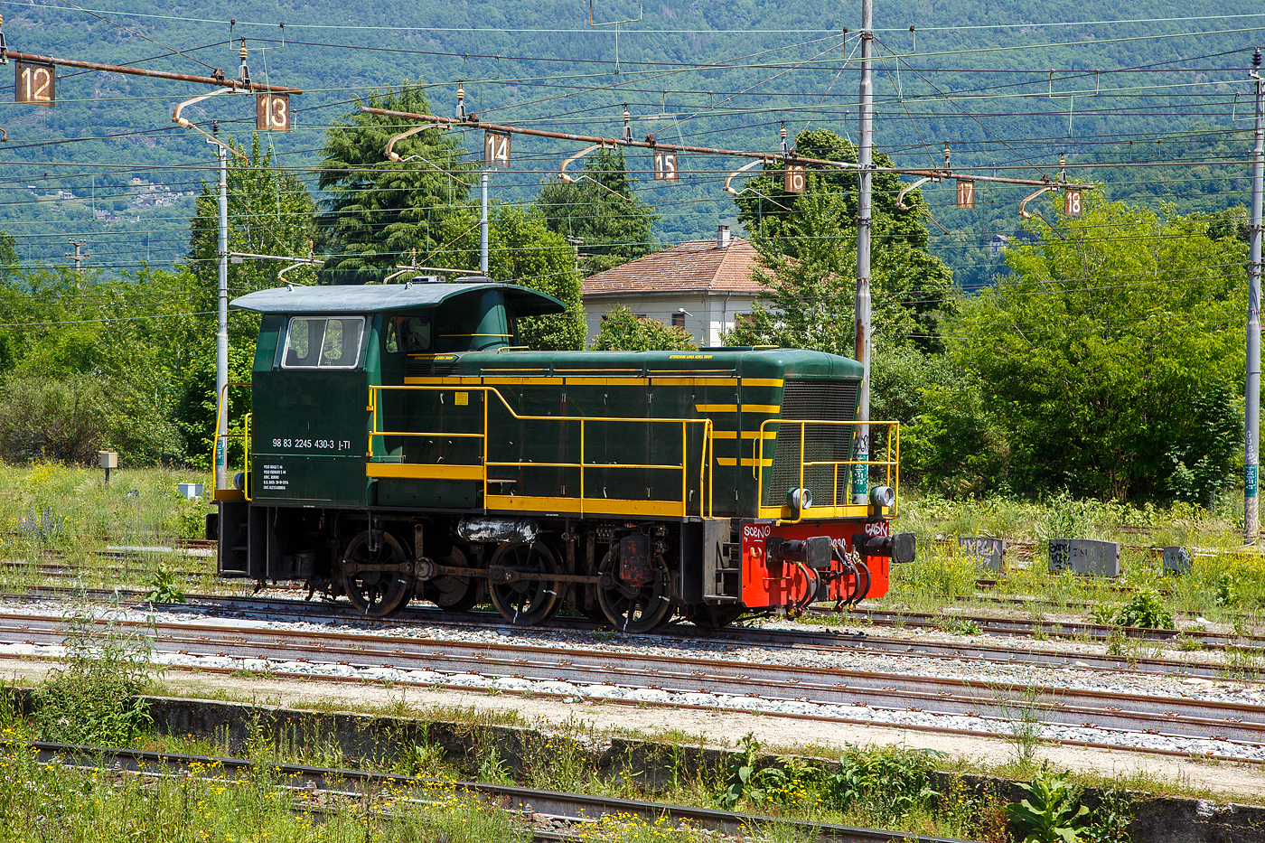 Die italienische Dieselrangierlok D.245.2230 (98 83 2245 430-3 I-TI) der Trenitalia (100-prozentige Tochtergesellschaft der FS), ist am 26.05.2023 im Bahnhof Domodossola abgestellt.

Die FS (Ferrovie dello Stato Italiane S.p.A. / Italienische Staatseisenbahnen AG) f�hrte 1963 die Reihe D.245 als leistungsf�higste Rangierlok ein. Die dreiachsigen Kraftpakete (Achsfolge C) wurden von verschiedenen Firmen in unterschiedlichen Formen geliefert.

Die Formen ergeben sich aus den unterschiedlichen Serien, Herstellern und Baujahren und sind wie folgt:
245.6001–6124, Baujahre 1963 bis 1969, Cantieri Navali Riuniti/OM/Jenbacher Werke
245.0001–0058, Baujahre 1964 bis 1968, Hersteller: Antonio Badoni/OM
245.1001–1020, Baujahre 1964 bis 1968, Hersteller: OM/FIAT-Mercedes-Benz
245.2001–2020, Baujahr 1966, Hersteller: Officine Meccaniche Reggiane/Breda
245.2101–2286, Baujahre 1976 bis 1987, Hersteller: Breda/Antonio Badoni/Greco/Ferrosud/IMMER
245.8001–8003, Baujahre 1958 bis 1962, dies waren sp�ter von der FS von einem Unternehmen erworben drei Lokomotiven vom Typ Jung R42C, die sp�ter zur Hafenbahn Genua kamen.

Sie hat ein hydraulisches Getriebe und Stangenantrieb. Die Achsen werden mittels Kuppelstangen von einer Blindwelle (zwischen der 2. Und 3. Achse) angetrieben. Die Lok hat einen, von 440 auf 370 kW, gedrosselten 12-Zylinderdieselmotor vom Typ Breda ID36, der die Leistung auf das Voith Str�mungsgetriebe (hydrostatisch), vom Typ L24. Die Dauerabtriebsleistung betr�gt 275 kW. Die Kraft�bertragung erfolgt �ber eine zwischen dem 2. und 3. Radsatz liegenden Blindwelle, Blindwellenkurbeln an den beiden Blindwellenenden und Kuppelstangen auf die R�der der Lok.

Technische Daten:
Spurweite: 1.435 mm (Normalspur)
Achsformel: C
L�nge �ber Puffer: 9.240 mm
Achsabst�nde: 1.500 / 2.500 mm
Eigengewicht: 46 t
H�chstgeschwindigkeit: 64 km/h (im Rangiergang 32 km/h)
Motorleistung: 370 kW
Dauerleistung: 275 kW
Treibraddurchmesser: 1.040 mm  