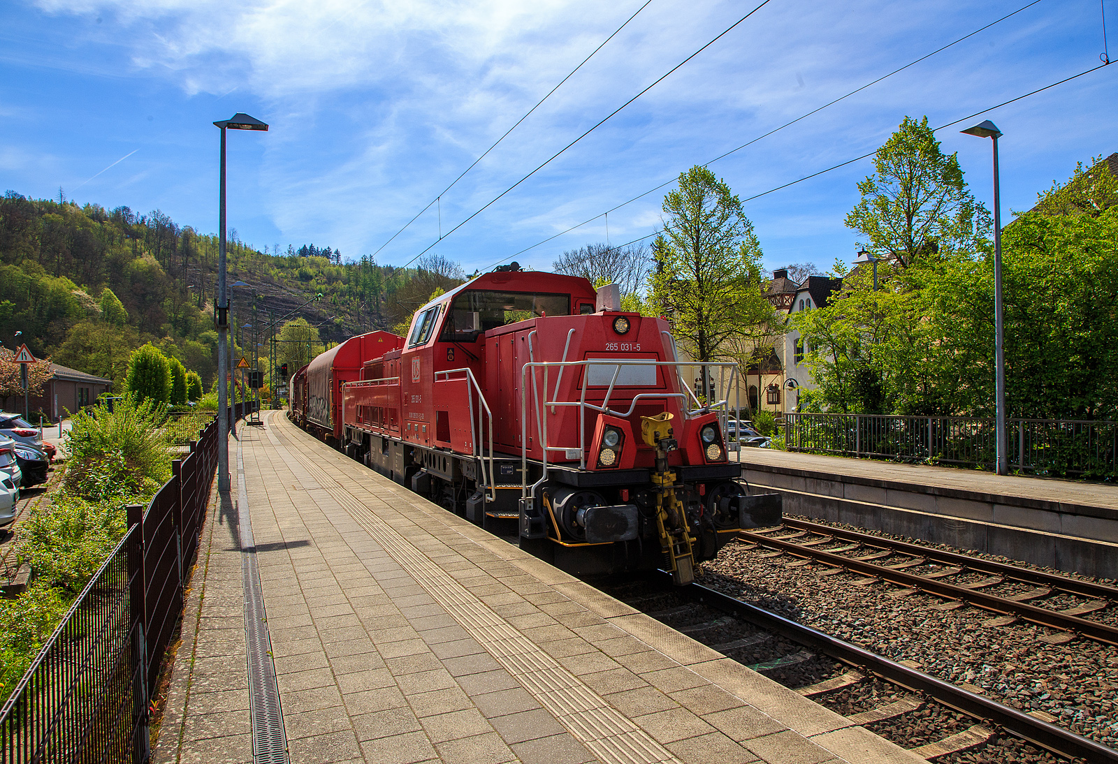 Die Kreuztaler 265 031-5 (92 80 1265 031-5 D-DB), eine Voith Gravita 15L BB der DB Cargo AG, fährt am 04.05.2023 mit einem Coilzug (Wagen der Gattung Shimmns) durch den Bahnhof Kirchen (Sieg) in Richtung Siegen bzw. Kreuztal.

Die Lok wurde 2013 von Voith in Kiel unter der Fabriknummer L04-18032 gebaut und an die DB Schenker (heute DB Cargo Deutschland AG) geliefert.

Die vierachsigen dieselhydraulischen Lokomotiven vom Typ Gravita 15L BB (BR 265) haben einen Leistung von 1.800 kW und habe somit 800 kW mehr Leistung als eine Gravita 10 BB (BR 261). Zudem sind sie über 1m länger als die kleine Schwester.

TECHNISCHE DATEN:
Spurweite: 1.435 mm
Länge über Puffer: 16.860 mm
Drehzapfenabstand: 8.200 mm
Drehgestell-Mittenabstand: 2.400 mm
größte Breite: 3.075 mm
größte Höhe über SOK: 4.273 mm
Raddurchmesser neu: 1.000 mm
kleinster bef. Gleisbogen: 80 m
Eigengewicht: 84 t
Kraftstoffvorrat: 5.000 l
Motor: V-12-Zylinder-Dieselmotor MTU 12V 4000 R43
Leistung: 1.800 kW bei 1.800 U/min
Getriebe: Voith L 5r4 zseU2
Anfahrzugkraft: 270 kN
Höchstgeschwindigkeit: 100 km/h
Tankvolumen: 5.000 l
Gebaute Stückzahl: 36
