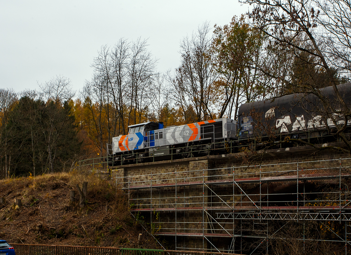 Die KSW 42 bzw. 277 902-3 (92 80 1277 902-3 D-KSW) der KSW (Kreisbahn Siegen-Wittgenstein) f�hrt am 14 November 2025, mit ihrem t�glichen �bergabeg�terzug (leere Coilwagen) von Herdorf in Richtung Betzdorf. Hier auf der Hellerbr�cke zwischen Herdorf und Sassenroth.

Nach dem Umsetzen (Richtungswechsel) in Betzdorf geht es dann �ber Siegen nach Kreuztal. 