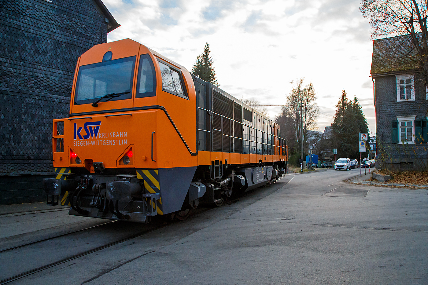 Die KSW 43 (92 80 1273 018-2 D-KSW), die asymmetrische Vossloh G 2000 BB der KSW (Kreisbahn Siegen-Wittgenstein) fährt am 14.12.2022 von Salchendorf kommend als Lz (Lokzug) durch Neunkirchen/Siegerland in Richtung Herdorf, hier überquert sie gerade die Kreuzung Bahnhofsstraße / Wiesenstraße. Hier ist sie mal kurz eine Straßenbahn. Die Strecke „Freien Grunder Eisenbahn“ (NE 447 / DB-Nr. 9275) von Herdorf nach Neunkirchen-Salchendorf (ehemals Pfannenberger Einigkeit) ist eine private Strecke (Infrastruktur) der Kreisbahn Siegen-Wittgenstein.

Nochmal einen lieben Gruß an das KSW Personal zurück. 
