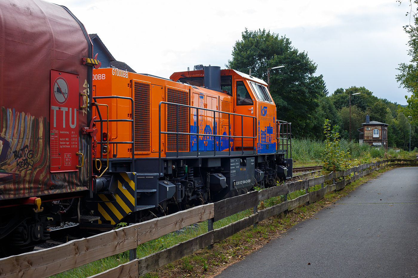 Die KSW 44 (92 80 1271 004-4 D-KSW) eine MaK G 1000 BB der KSW (Kreisbahn Siegen-Wittgenstein), steht am 12 September 2024 mit einem Übergabezug (leere Wagen), auf ihren Rangierbahnhof in Herdorf der Betriebsstätte FGE -Freien Grunder Eisenbahn (KSW NE447 / DB-Nr. 9275), vor der geschlossenen Gleisspeere, zur Abfahrt bereit. Aber noch muss sie den Gegenverkehr abwarten, bevor sie in Richtung Betzdorf losfahren kann. Rechts ist dann die Weiche auf die DB-Strecke „Hellertalbahn“ (KBS 462) Betzdorf – Herdorf – Haiger. Hinten rechts das Weichenwärter Stellwerk Herdorf Ost (Ho). 

Die Lok 44 wurde 2003 unter der Fabriknummer 1001462 bei Vossloh gebaut und am 05.01.2004 an die SK - Siegener Kreisbahn GmbH geliefert, welche ab Ende 2004 nun als Kreisbahn Siegen-Wittgenstein (KSW) firmiert.