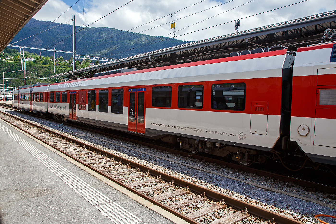 Die relativ vierachsige INOVA-Zwischenwagen mit Niederfluranteil f�r die NPZ Domino-Z�ge (RBe 560), gebaut 2008 bis 2009 durch Bombardier in Villeneuve. Hier der Wagen B NPZ DO RA 50 85 29-43 407-0 CH-RA der RegionAlps, eingereiht in den RA 12 (RBDe 560 412-9) am 25.05.2023 im Bahnhof Brig. Die Wagen der  RegionAlps SA tragen den Werbespruch f�r die Region auf Deutsch und Franz�sisch (Wallis, in mein Herz eingebrannt / Valais, Grav� dans mon coeur). Die Wagen haben ein rollstuhlg�ngiges und damit behindertengerechtes WC erhalten.

TECHNISCHE DATEN:
Spurweite:  1.435 mm (Normalspur)
Anzahl der Achsen: 4
L�nge �ber Puffer:  24.700 mm 
Drehzapfenabstand: 18.900 mm 
Achsabstand im Drehgestell: 2.500 mm
Gewicht:  36 t 
H�chstgeschwindigkeit: 140 km/h
Sitzpl�tze: 60

Die Regionalps (RA) ist ein Eisenbahnverkehrsunternehmen im Kanton Wallis, mit Sitz in Martigny hat. Eigent�mer derim Jahr 2003 gegr�ndete Gesellschaft  sind die Schweizerischen Bundesbahnen (SBB) mit 70 %, die Transports de Martigny et R�gions (TMR) mit 18 % und der Kanton Wallis mit 12 %. Die RA betreibt den Regionalverkehr vor allem im Rhonetal zwischen dem Ostufer des Genfersees und Brig. Inzwischen geh�ren Regionalps 16 dreiteilige NPZ Domino (Trieb-, Zwischen- und Steuerwagen ex SBB) und 4 RABe 525 NINA (ex TMR).
