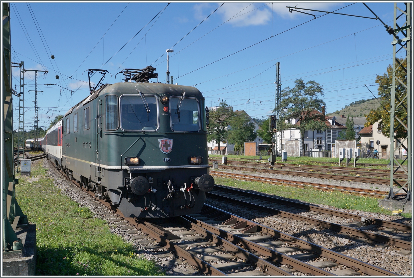 Die SBB Re 4/4 II 11161 in ihrer grünen Lackierung erreicht mit einem IC von Zürich nach Stuttgart den Bahnhof Singen. 

Die grüne Farbe ist übrigens NICHT die Ursprungs-Lackierung der Re 4/4 II 11161, die Lok wurde 1967 in TEE Farben ausgeliefert und bekam erst nach dem Ende des TEE-Einsatzes 1981/82 die heutige grüne Lackierung. 19. September 2022