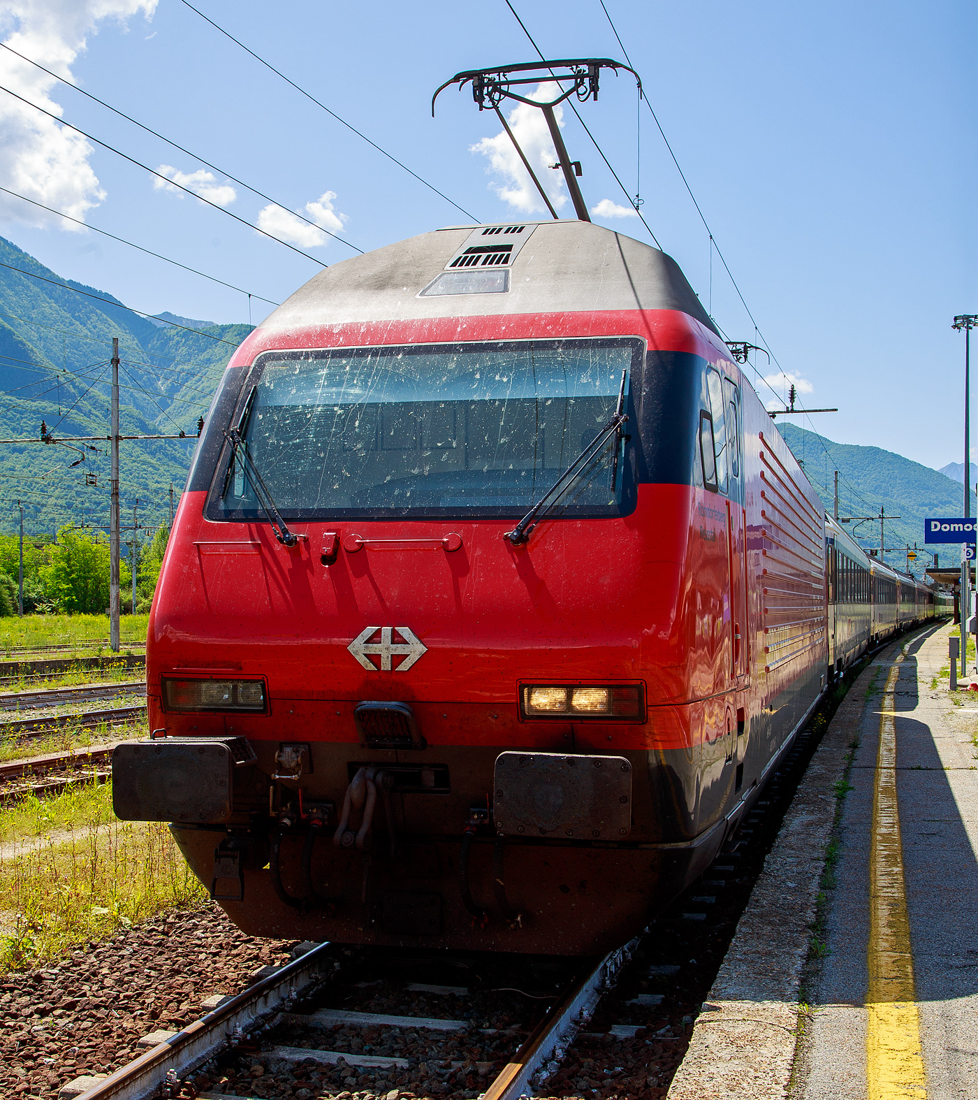 Die SBB Re 460 016-0  Rohrdorferberg Reusstal   (91 85 4 460 016-0 CH-SBB) hat am 26 Mai 2023 mit dem IR 3017 (Brig – Domodossola) den Zielbahnhof Domodossola (I) erreicht und ist nun mit dem Zug auf Gleis 6 abgestellt. Nach gut 2 ½ Stunden (um 13:48 Uhr) geht es dann als IR3022 von Domodossola zurück nach Brig.

Die Lok2000 wurde 1992 von der SLM (Schweizerischen Lokomotiv- und Maschinenfabrik in Winterthur) unter der Fabriknummer 5477 gebaut, der elektrische Teil ist von der ABB (Asea Brown Boveri). Sie war 2015 der 2. Prototyp der im SBB Werk Yverdon-les-Bains (VD) das vollständige Modernisierungs-/Refit-Programm LOK2000 durchlief. So sollen die Loks fit für die nächsten 20 Jahre sein, zudem werden durch alle 119 SBB Re 460 Lokomotiven so etwa 30 Gigawattstunden Energie eingespart.