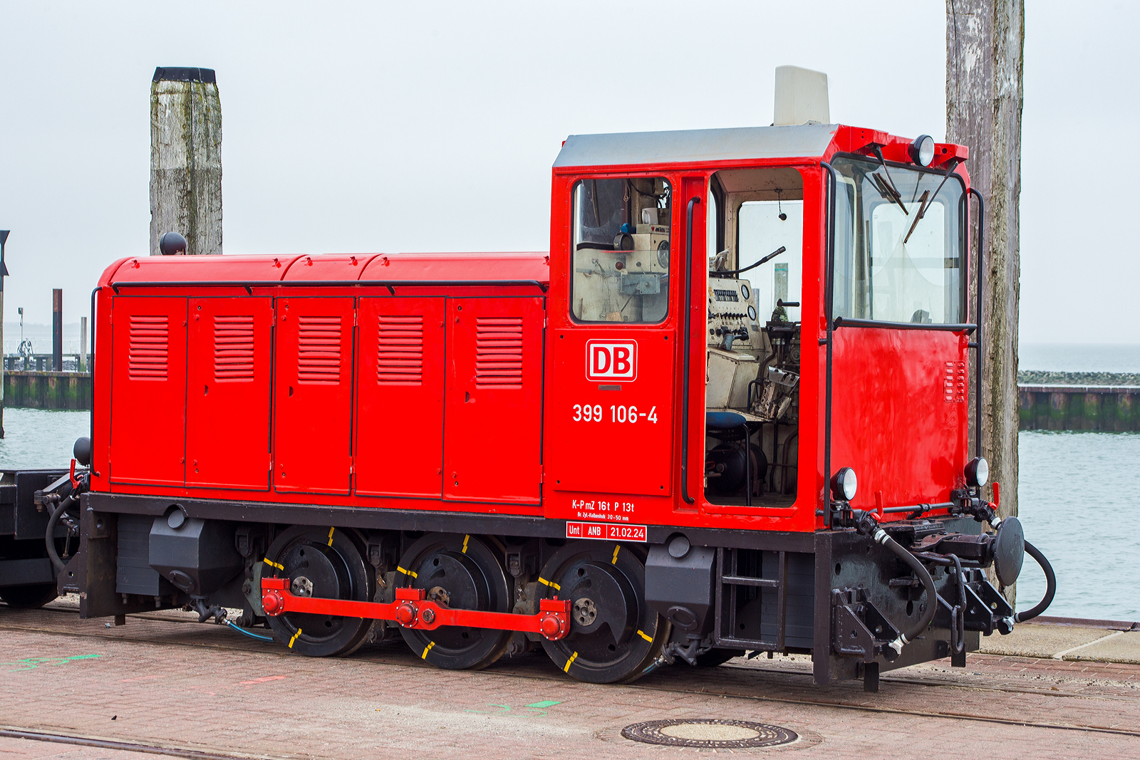 Die schmalspurige Diesellok 399 106-4 (98 80 3399 106-4 D-DB), eine der DB Fernverkehr AG bzw. der Wangerooger Inselbahn / SIW - Schifffahrt und Inselbahn Wangerooge steht am 13 März 2024, nun mit einem leeren Güterzug bestehend aus vierachsiger schmalspuriger Flachwagen DB 630xx, am Westanleger der friesischen Insel Wangerooge. Zuvor war der Güterzug beladen und wurde bereits mittels (20 t) Schwerlastgabelstapler entladen, bevor er wieder beladen wird, dies dauert aber gerade noch etwas, da gerade auch die Personenfähre MS Harlingerland angekommen ist.

Noch vor der Gründung der DB AG beschaffte die Deutsche Bundesbahn im Jahr 1992 zwei dreiachsige Kleinloks des rumänischen Typs Faur L18H vom ehemaligen Mansfeld-Kombinat für den Einsatz auf der Inselbahn Wangerooge. Sie sollten zunächst die Altbaulokomotiven der Baureihe 329 unterstützen, konnten aber die in sie gesetzten Erwartungen nicht erfüllen. Sie werden daher bis heute meist für kurze Güterzüge und als Reserve für die Personenzüge vorgehalten, wenn die Maschinen 399 107 und 399 108 nicht zur Verfügung stehen.

Die meterspurige Lok wurde 1990 vom rumänischen Hersteller FAUR S.A.(bis 1989 Faur Lokomotivwerke 23. August) in Bukarest unter der Fabriknummer 25666 gebaut und im April 1990 an das MKWP - VEB Mansfeld-Kombinat  Wilhelm Pieck  geliefert, wo sie kurz bei der zum Kombinat gehörenden meterspurige Schlackenbahn der August-Bebel-Hütte, ehemals bis 1951 Kochhütte, (eine Kupferhütte) in Helbra im Einsatz war. Am 10. September 1990 erfolgte der letzte Ofenabstich auf der Kochhütte. Die Gebäude und Betriebsanlagen wurden in den Folgejahren vollständig zurückgebaut, heute befindet sich hier ein Gewerbegebiet. So wurde bereits im November 1992 die Lok, wie eine weitere (399 105-6), an die DB - Deutsche Bundesbahn für die Wangerooger Inselbahn verkauft. Bevor sie dort zum Einsatz kam erfolgte im BW Wangerooge im Juli 1993 ein Umbau bzw. Anpassung an die EBO-Richtlinien und DB-Standards.

Insgesamt wurden zehn Diesellokomotiven der Baureihe L18H vom rumänischen Fahrzeug- und Maschinenherstellers FAUR zwischen 1983 und 1990 für verschiedene schmalspurige Wald- und Industriebahnen in Osteuropa gebaut. Es handelt sich um dreiachsige, stangengekuppelte Maschinen mit einem einseitigem Motorvorbau und Endführerstand sowie Antrieb in Z-Anordnung. Als Antrieb dient ein direkt angeflanschter Drehmomentwandler mit Lastschaltgetriebe und Achsgetriebe auf dem ersten Radsatz.

TECHNISCHE DATEN:
Spurweite: 	1.000 mm (Meterspur)
Achsformel: C
Länge über Puffer: 5250 mm
Höhe: 2.800 mm
Breite: 1.800 mm
Achsabstand: 2 x 900 = 1.800 mm
Treibraddurchmesser: 	750 mm
Kleinster befahrbarer Gleisbogen: R 20 m
Leergewicht: 16,0 t
Höchstgeschwindigkeit: 	28 km/h
Installierte Leistung: 132 kW
Motorentyp:  MAN (Lizenzbau) D2156 HM N8
Motorbauart: 6-Zylinder-Reihenmotor mit 10.350 cm³ Hubraum
Nenndrehzahl: 1.800/min
Leistungsübertragung: hydrodynamisch und mechanisch
Bremse: Druckluft
Lokbremse: Druckluft, indirekt
Kupplungstyp: Balancierhebel- bzw. Ausgleichkupplung (zp2)
