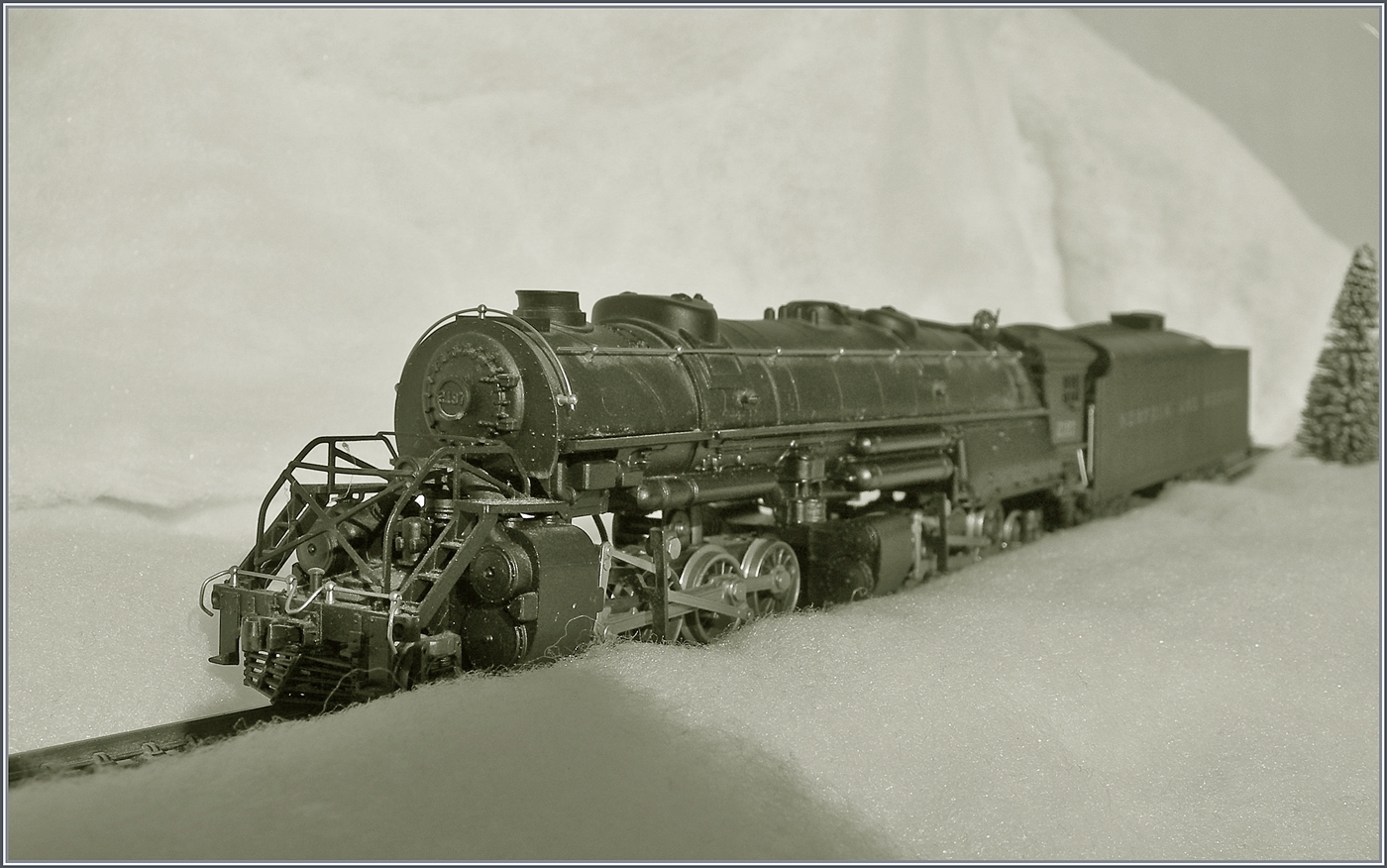 Die selbst in H0 mächtige Mallet Dampflok 2-8-8-2 - Y6b 2197 der Norfolk & Western kämpft sich durch den Schnee. Die Konstruktion der Mallet Vorbildloks Loks basiert Angaben, welche die U.S.R.A. (United States Raitroad Administration) während des Ersten Weltkriegs eingeführt hat. Die die Loks der Klasse Y6b wurde ab 1936 ausgeliefert. Grundsätzlich wurde die Klasse Y6b so konstruiert, dass sie schwere Güterzug mit 30 mp/h ziehen konnte, doch unter guten Bedingungen konnten auch bis zu 50 mp/h erreicht werden. 

Das Modell dieser Gelenklokomotive Typ Mallet „Y 6 b“ der  Norfolk & Western  dürfte gut 50 bis 60 Jahre alt sein und ist eine von der Grüsse her sehr beeindruckende Modellumsetzung. Nicht ganz logisch scheint mir, weshalb der Motor bei soviel Platz in das Führerhaus gequetscht wurde, um dann durch lange kardanischen Wellen die weit entfernten  Drehgestelle  anzutreiben. Der Tender ist vorbildgerecht mit zwei dreiachsigen  Buckeye -Drehgestellen ausgestattet, die auch zur Stromabnahme herangezogen werden. 

Das Modell dürfte gut zwanzig bis dreissig Jahre lang nicht mehr gefahren sein, nachdem ich das Modell zerlegt und bewegliche Teile entfettet und neu eingeölt habe, fährt es seit gestern wieder, auch wenn mir für den Auslauf des mächtigen Modell sowohl die Wagen als auch die Strecke fehlt. 

12. Jan. 2025