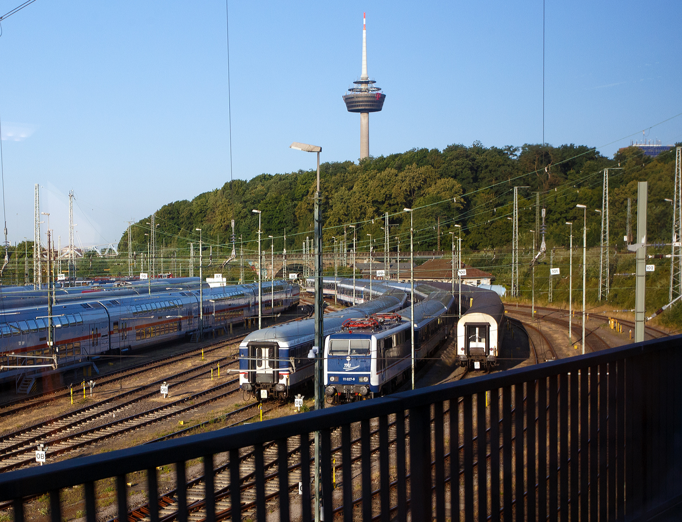 Die TRI 111 027-9 (91 80 6111 027-9 D-TRAIN) der TRI Train Rental GbR (Eckental-Eschenau) in National Express Lackierung steht am 01 Juli 2025 beim DB Betriebsbahnhof Köln (Gladbacher Wall).

Die Lok wurde 1976 von Krauss-Maffei in München-Allach unter der Fabriknummer 19764 gebaut und als 111 027-9 an die Deutsche Bundesbahn geliefert. Der elektrische Teil ist von Siemens. 2023 wurde sie von der DB Regio AG an die TRI Train Rental GbR verkauft. Sie besitzt eine Konventionelle-Wendezug-Steuerung (36-poliges Kabel), eine Zeitmultiplexe-Wendezug-Steuerung (UIC-Kabel) und eine Zeitmultiplexe-Doppeltraktions-Steuerung (UIC-Kabel).

Vielleicht liegt es an der Lackierung, aber wenn ich hier nicht deutlich die Nummer hätte lesen können, dann wäre ich nicht gleich auf eine 111er gekommen.

Die TRI Train Rental GmbH ist ein deutsches Eisenbahnverkehrsunternehmen, welches sich der Erhaltung historischer Schienenfahrzeuge widmet. Über ihr eigentliches Ziel, die betriebsfähige Aufarbeitung eines Triebzugs der Baureihe 403 hinaus, hat sich TRI zu einem Dienstleister für Sonder-, Ersatz- und Notverkehre entwickelt. Im Dezember 2018 begann die TRI mit Fahrten des Verkehrsvertrages Sonderzüge NRW.